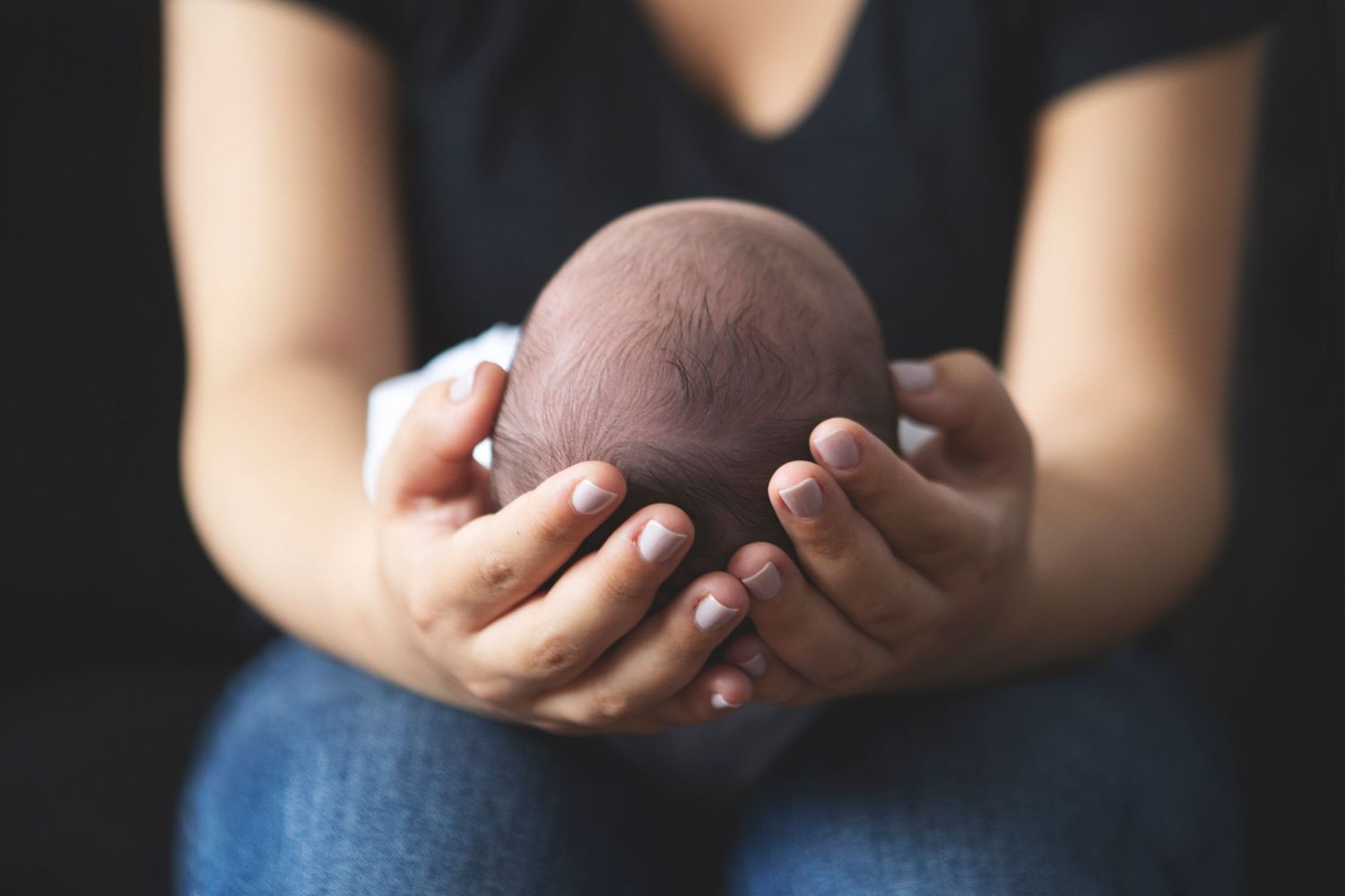 Tender moment as mum cradles her newborn baby  in a cosy living room in Prestwich, Manchester.