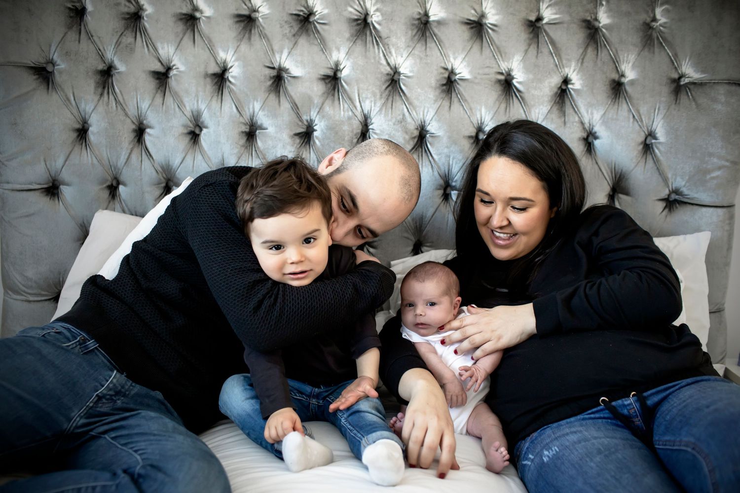 Family photography in Prestwich, Manchester, with a family of four posing on their bed during a newborn session