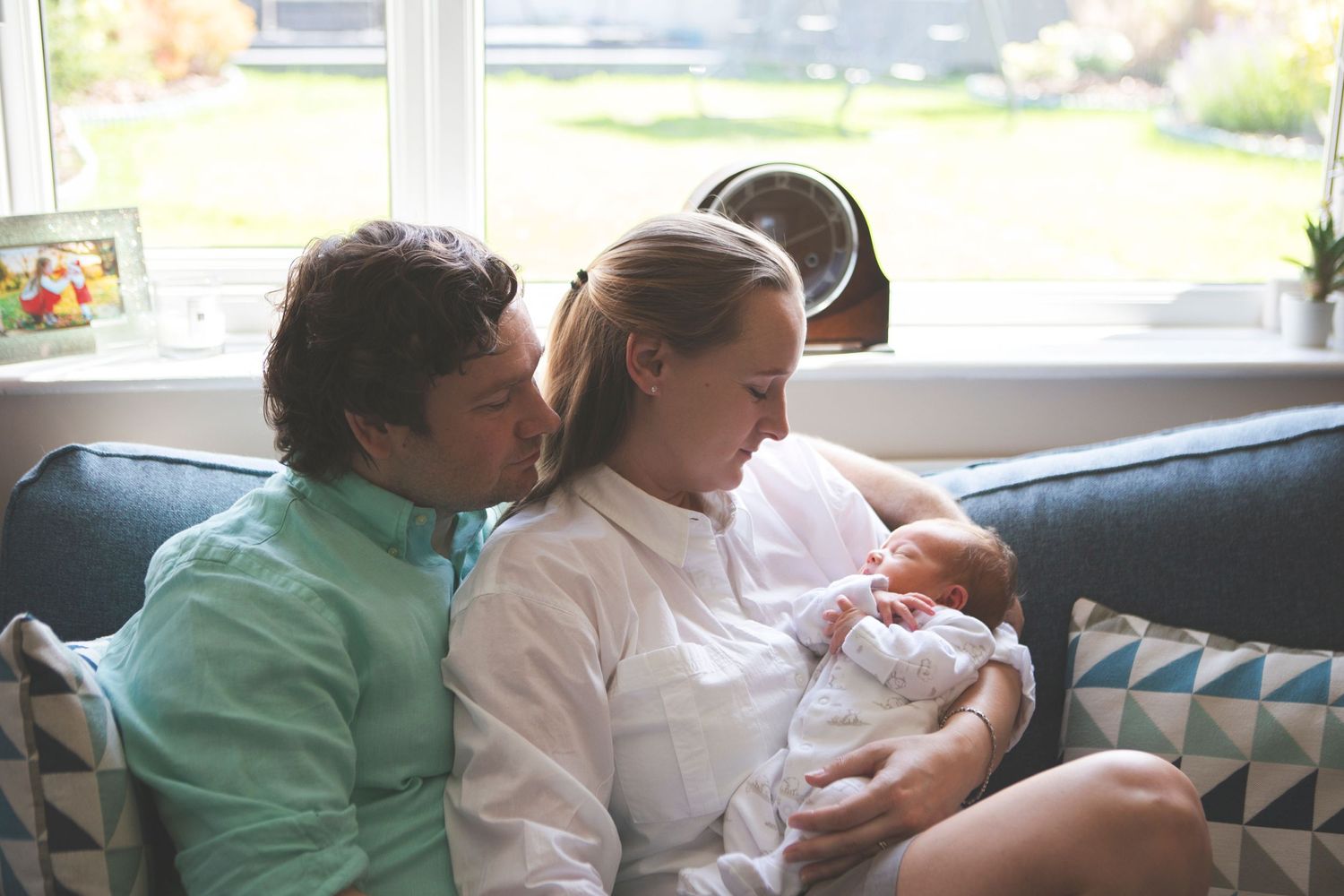 Family of three enjoying time together on the sofa during a newborn photoshoot in Prestwich, Manchester