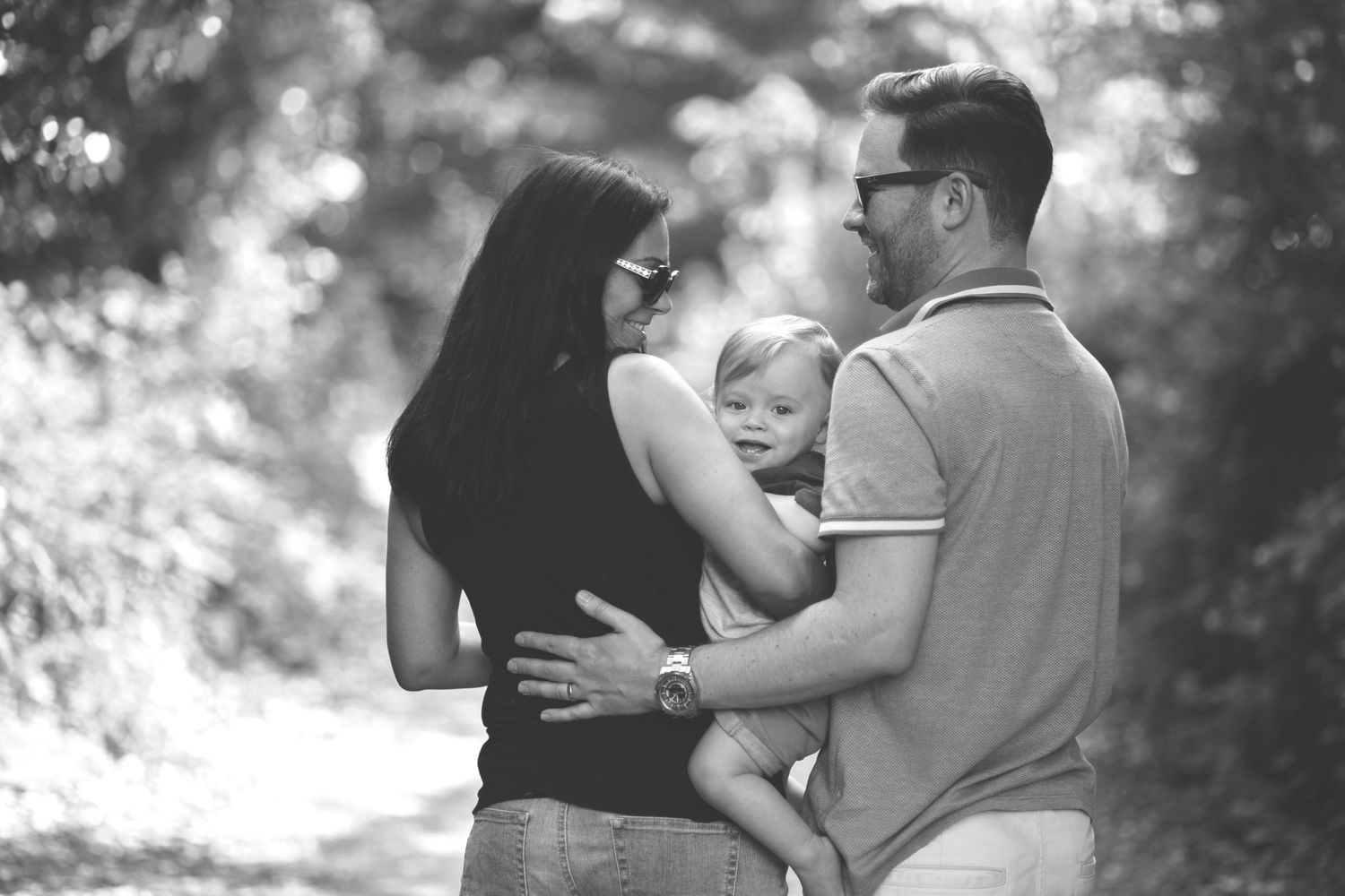 Lifestyle black and white photo of a family of three with their son, walking along a scenic trail in Manchester
