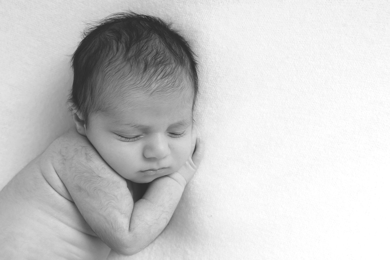Newborn baby photographed sleeping on a cosy blanket during a Prestwich-based photoshoot