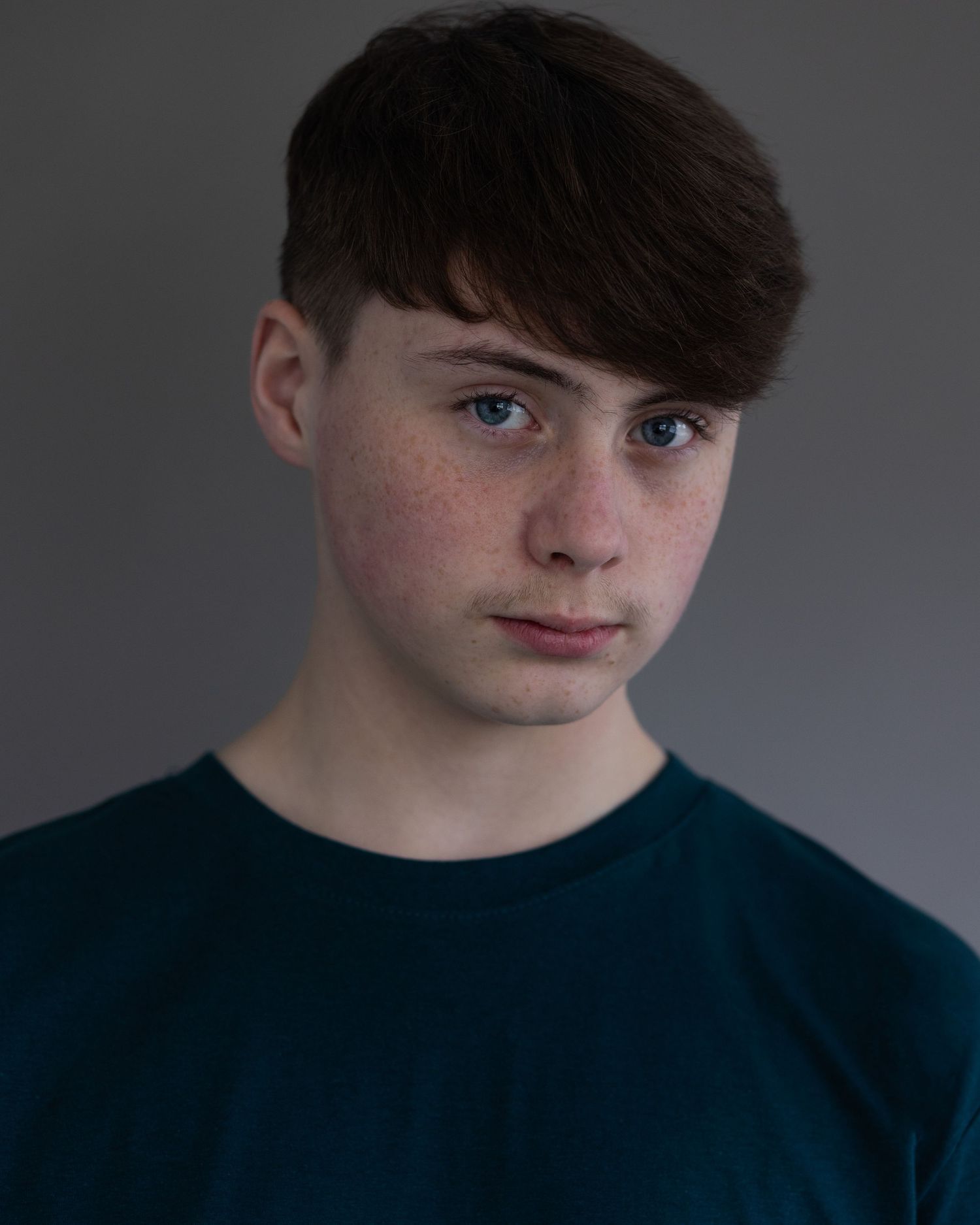 A dark-haired boy posing for an acting headshot, exuding confidence and charisma during a professional headshot session in Manchester.