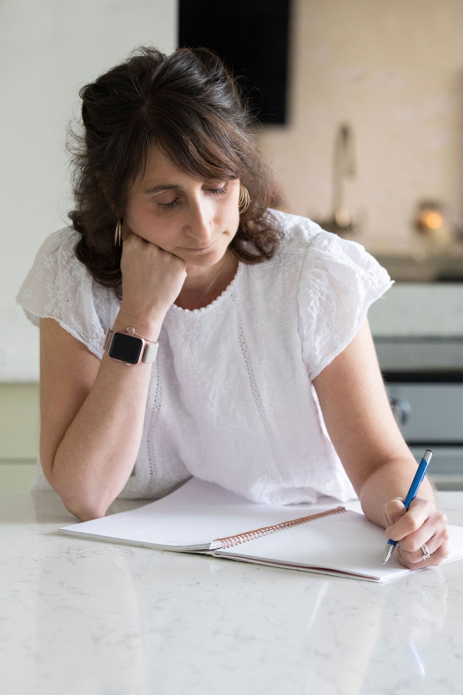 A woman writing at her kitchen table in Prestwich, focused and engaged, during a personal branding photo session