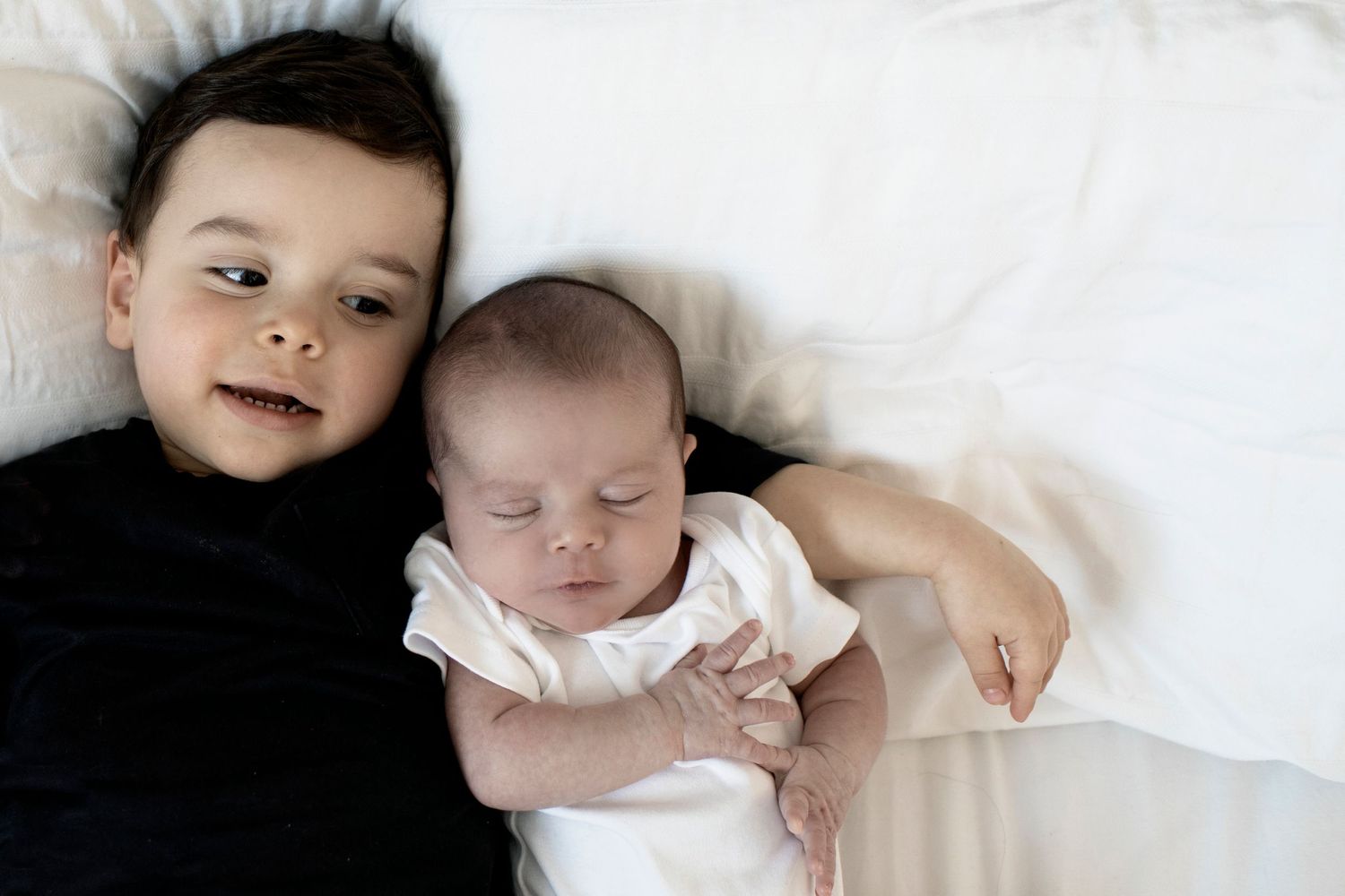 Newborn and family photography in Prestwich with siblings sharing a loving moment