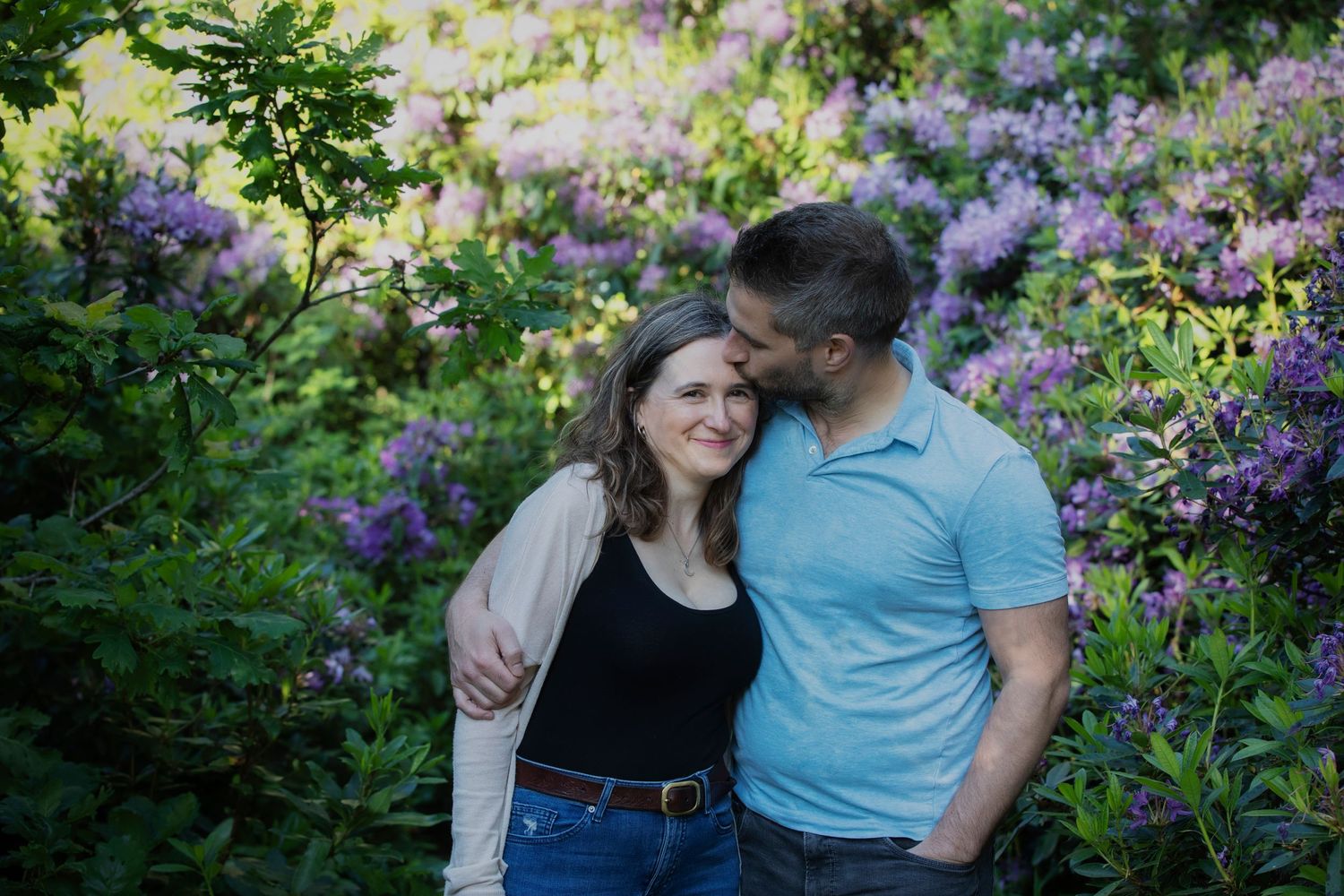 Tender moment of a husband kissing his wife on the forehead in a peaceful park, captured during a loving family photo session in Whitefield.