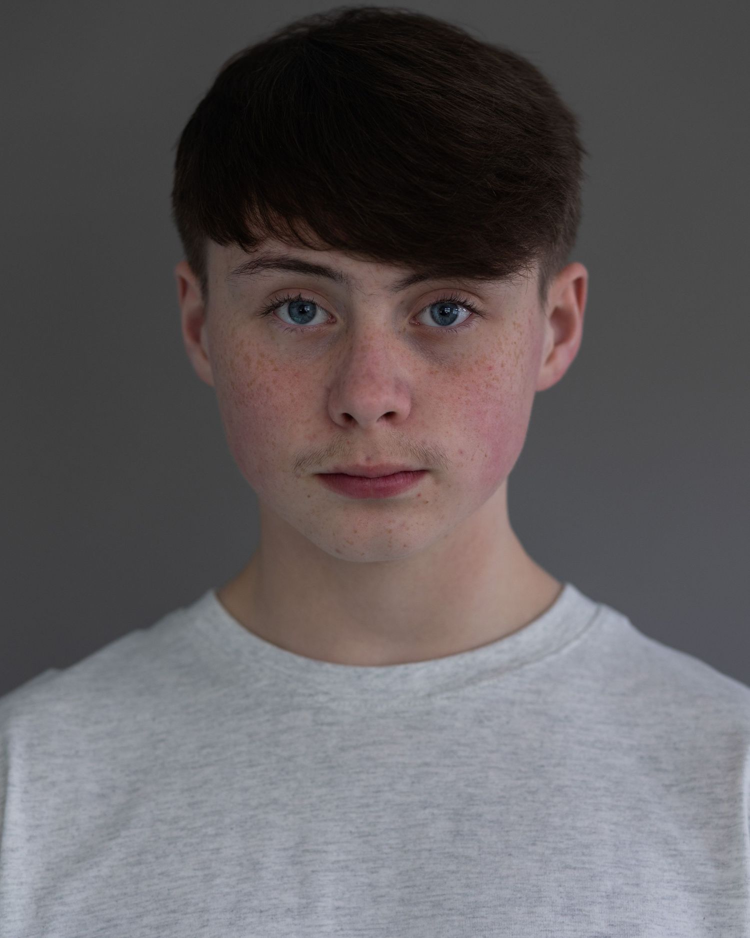 A dark-haired boy captured in an acting headshot, displaying confidence and poise during a professional branding session in Prestwich