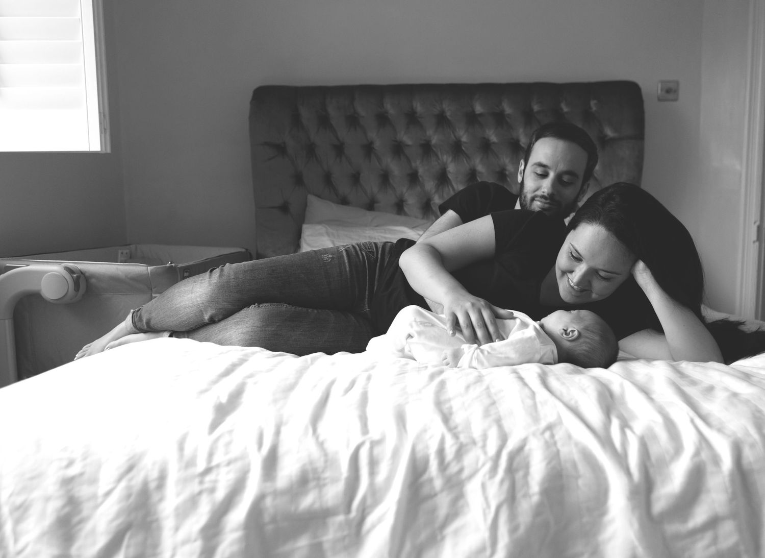 Mum and dad looking lovingly at their newborn baby in a soft, serene room in Prestwich