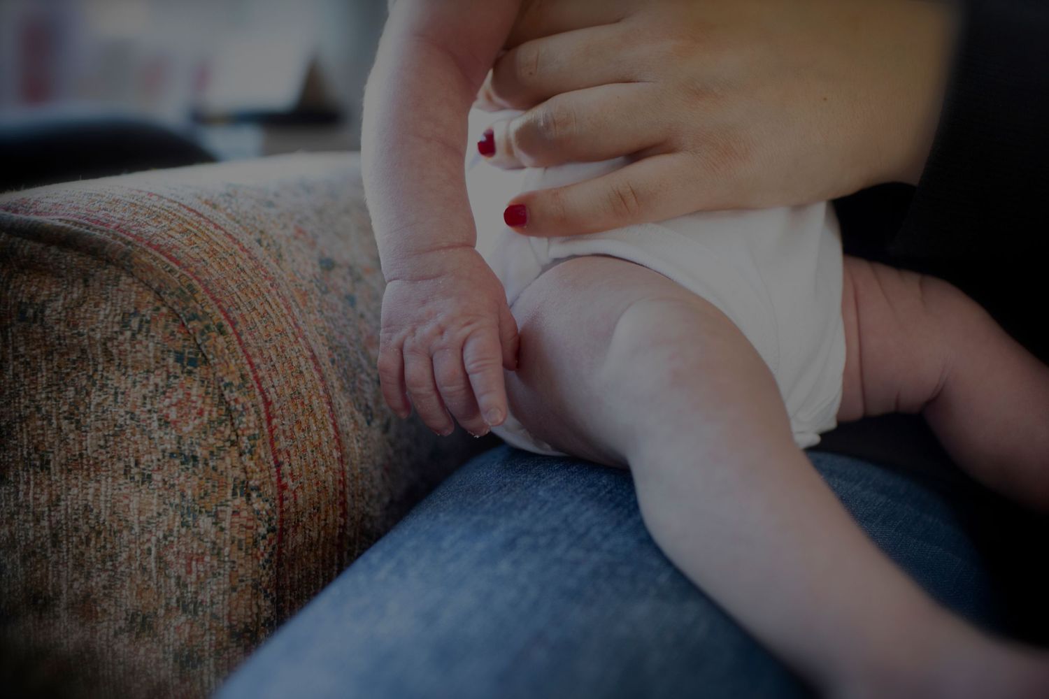 Close-up of a newborn’s tiny hand and leg with soft, neutral tones. Prestwich, Whitefield, UK