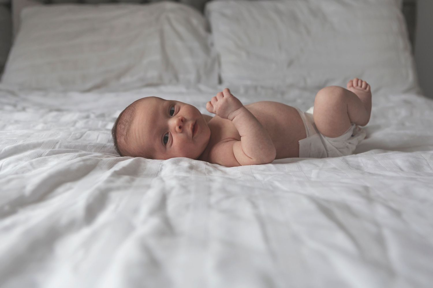 Cute newborn baby wearing a nappy, lying on a soft blanket in Whitefield, Manchester