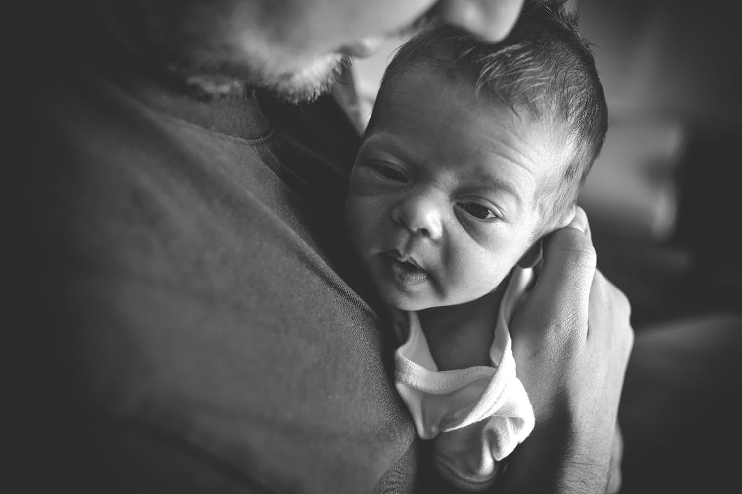 Dad holding his newborn baby with love in a calm and intimate setting in Prestwich, Manchester.