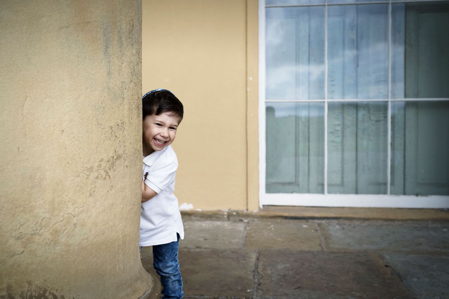 A young boy plays peek a boo and smiles during a family photo session in Prestwich, Manchester