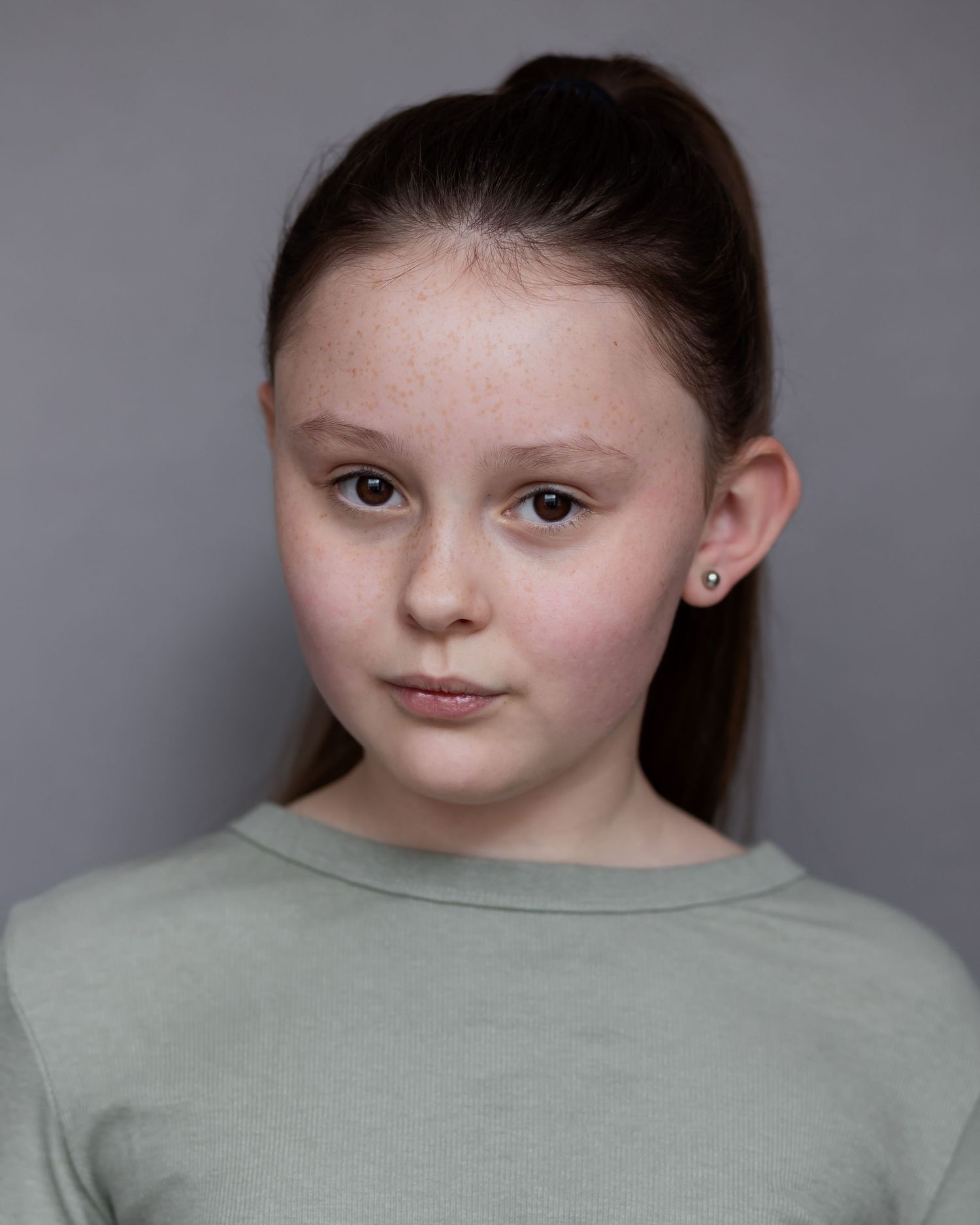 A girl with a ponytail posing for an acting headshot in Manchester, looking confident and ready for the camera during a professional session