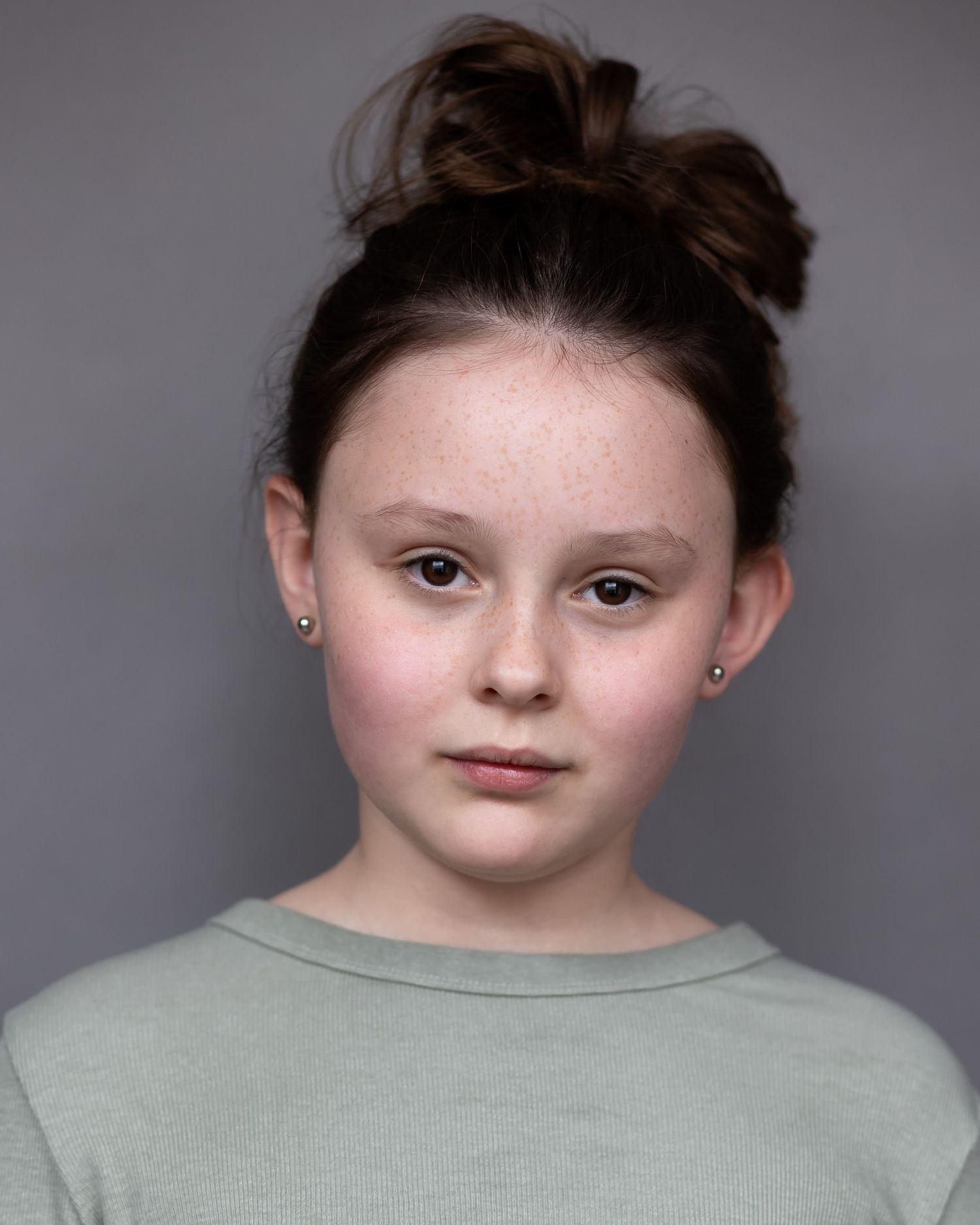 A girl with her hair in a bun posing for an acting headshot in Prestwich, exuding confidence and professionalism during a headshot session