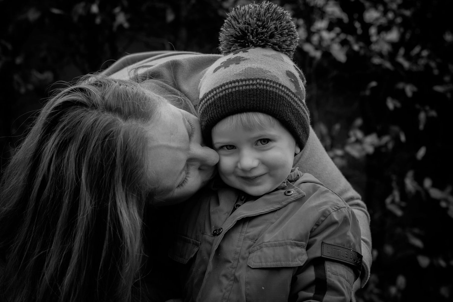 Mum kissing her son on the cheek in a family photo shoot at a local park in Bury, Manchester