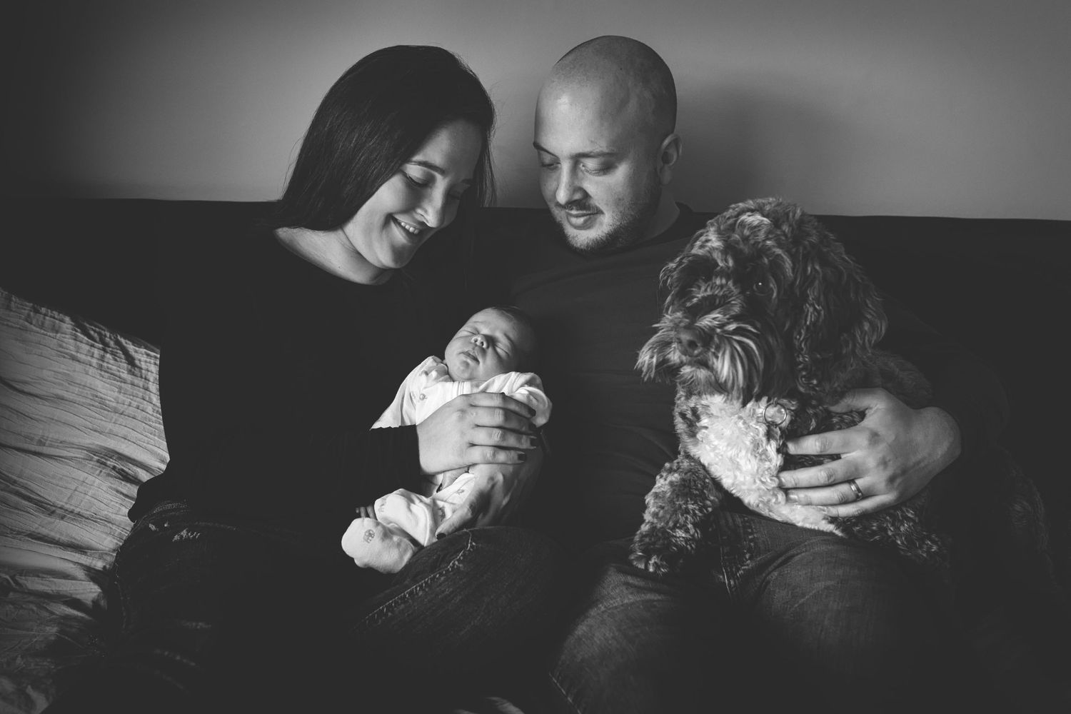 Smiling parents with their newborn baby during a family portrait session in Prestwich, Manchester