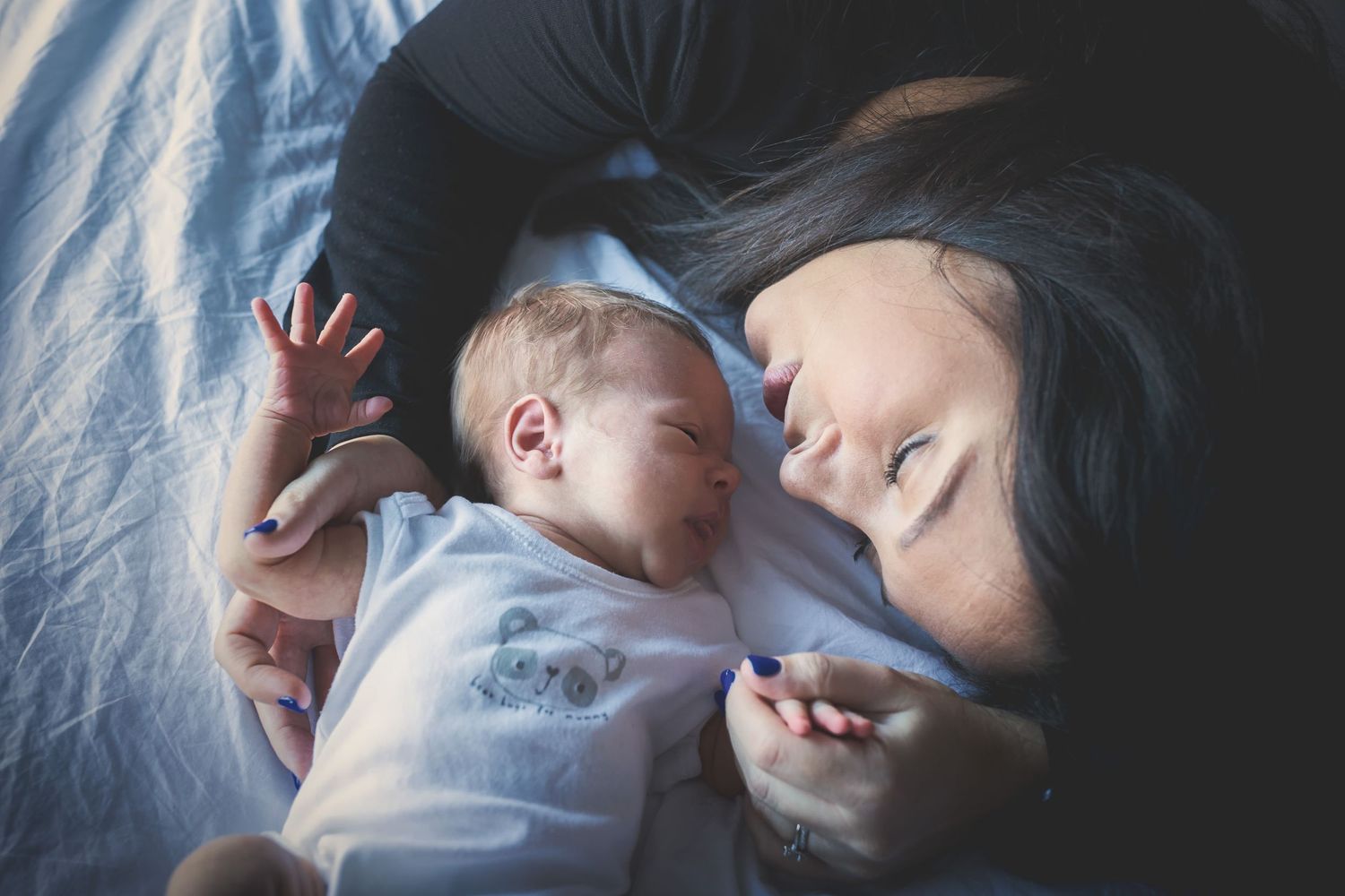 Mom gently kissing her newborn baby’s forehead, with a soft background in a Prestwich home