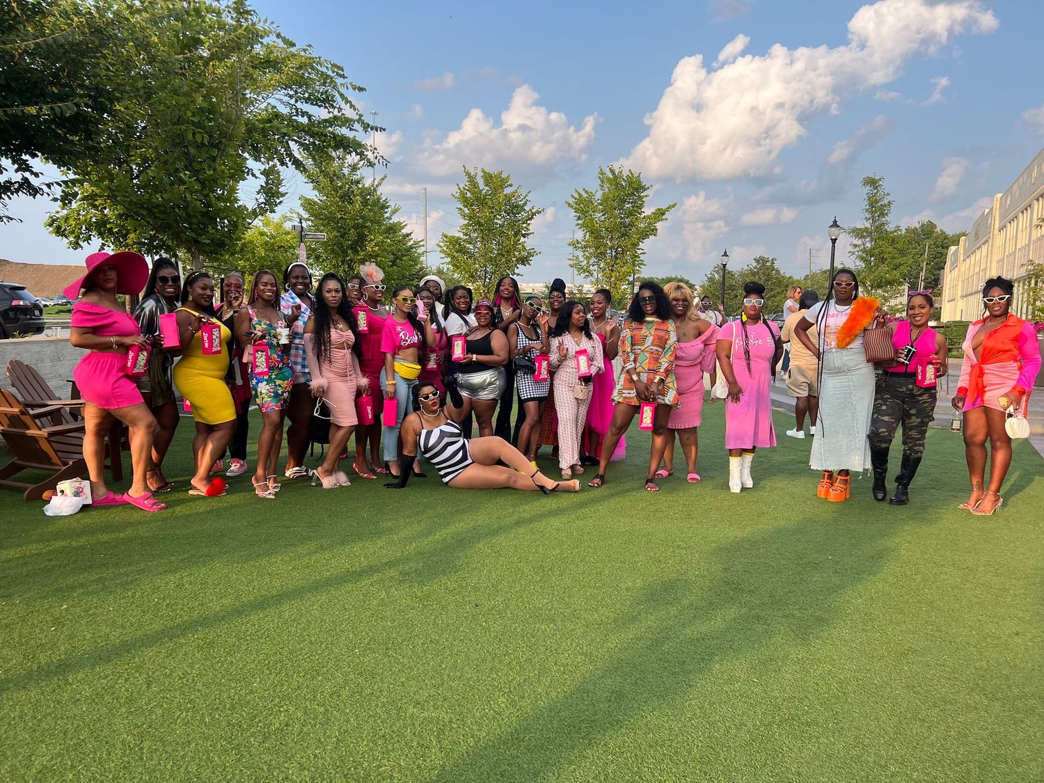 Large gathering of people in pink attire posing outdoors on grass.