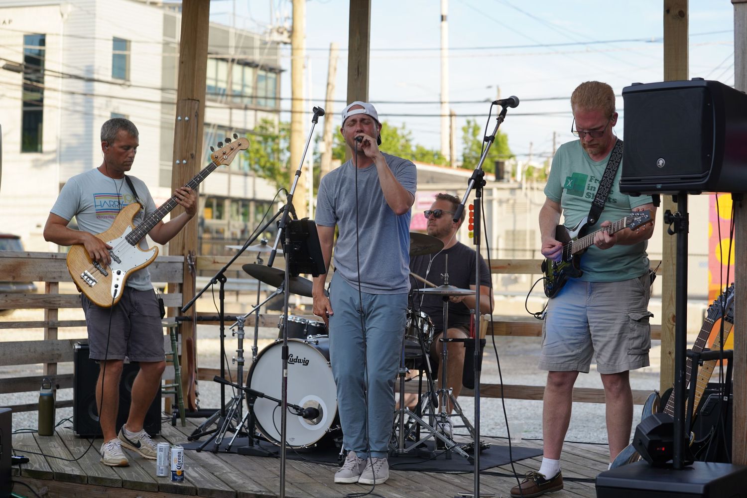 Live band performing on an outdoor stage with guitar, drums, and other instruments.