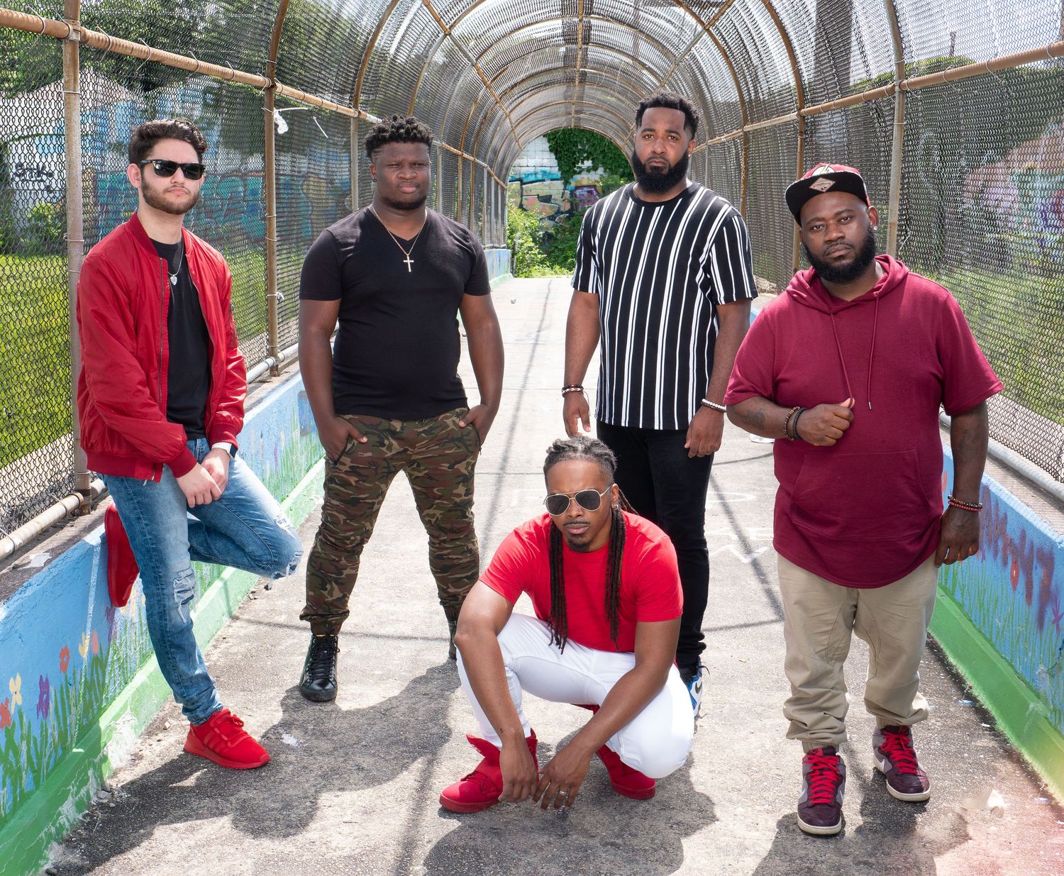 A group poses together under an outdoor covered walkway with painted walls.