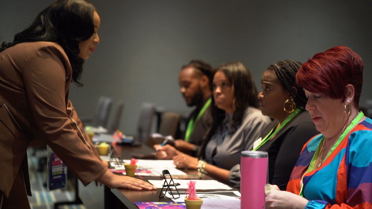 Conference attendees check in at a registration table while staff assists with paperwork.