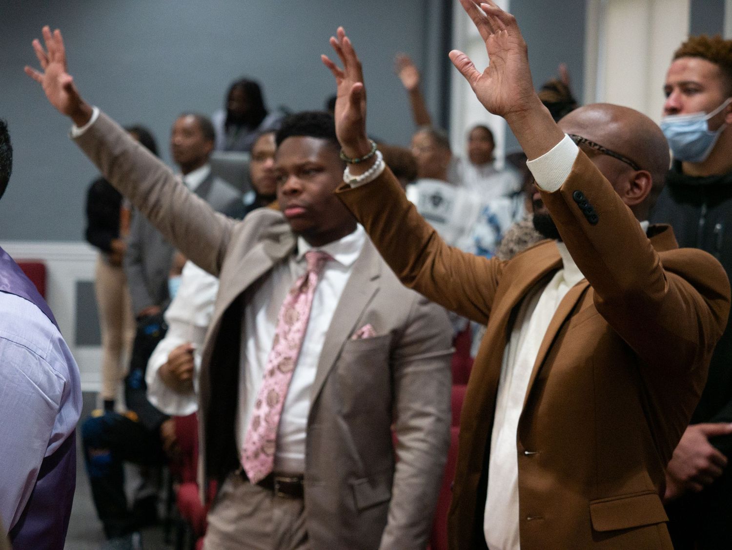 People raising their hands in worship during an indoor church service.