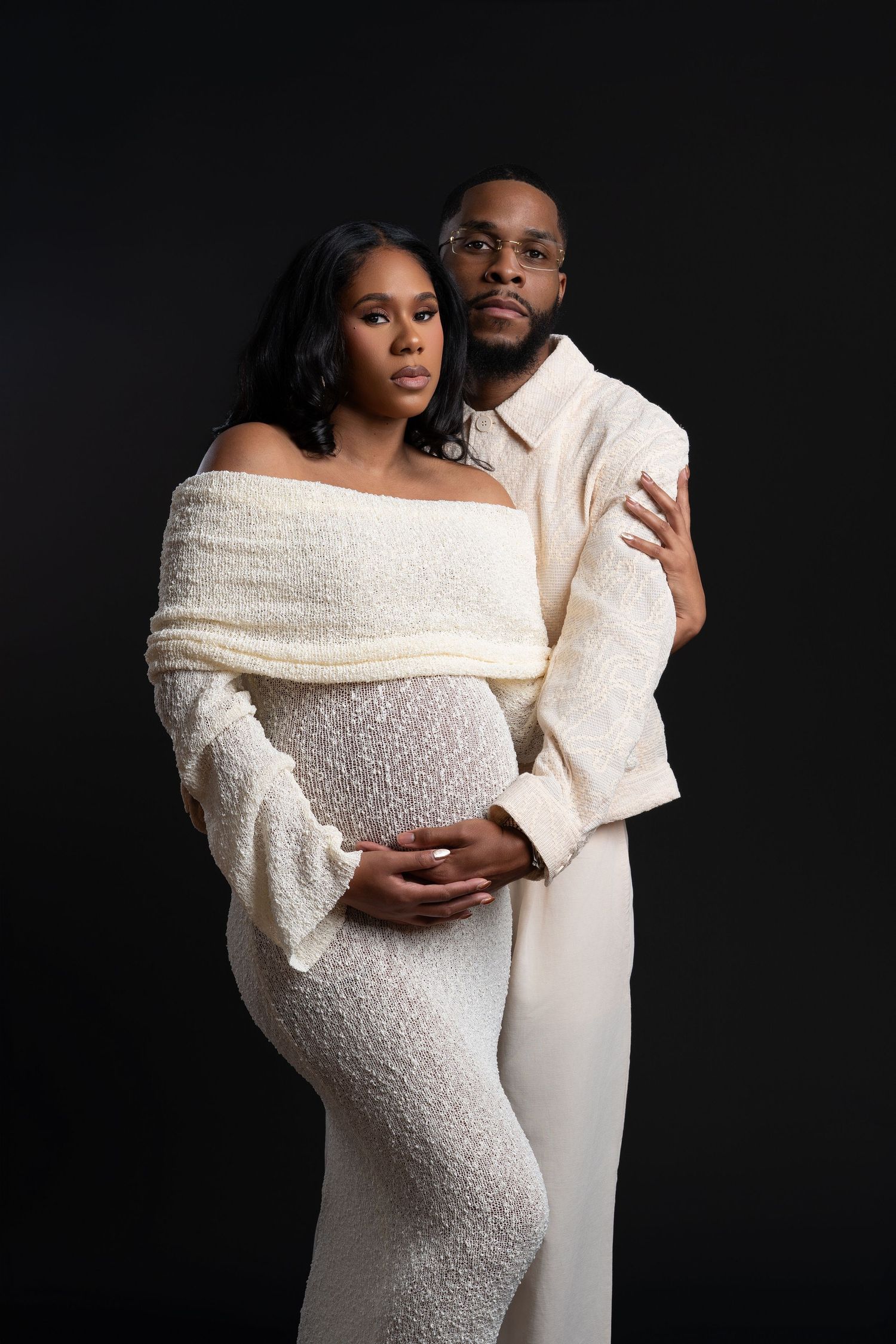 Stylish African American couple in coordinated white outfits during a studio maternity photoshoot in Chicago.