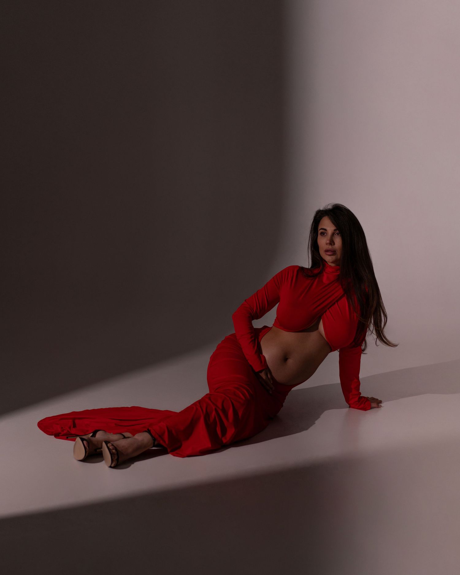 Pregnant women in a long red dress posing in a photo studio in Chicago.