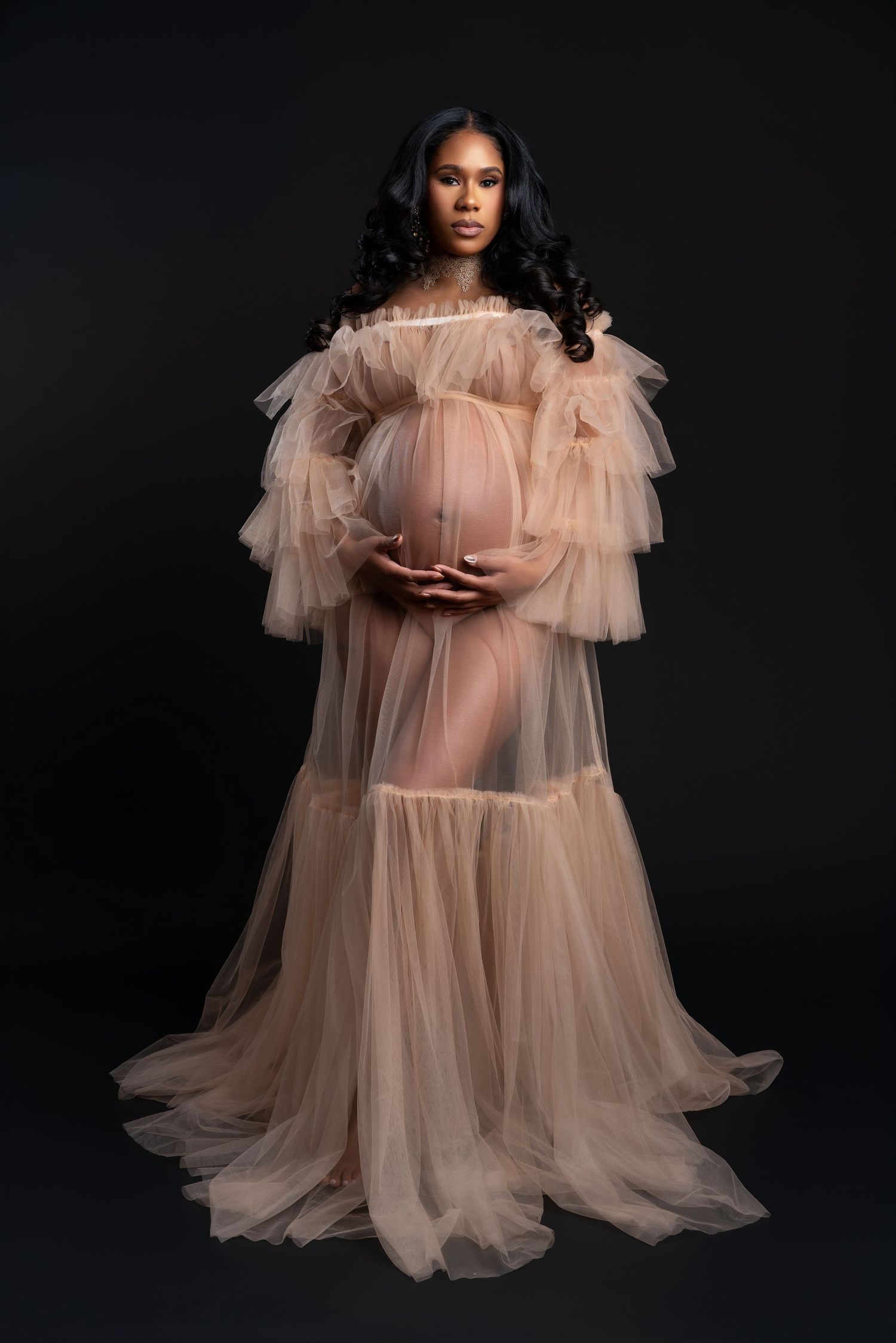 Expectant mother in a beige textured gown posing gracefully during her studio maternity session in Chicago.