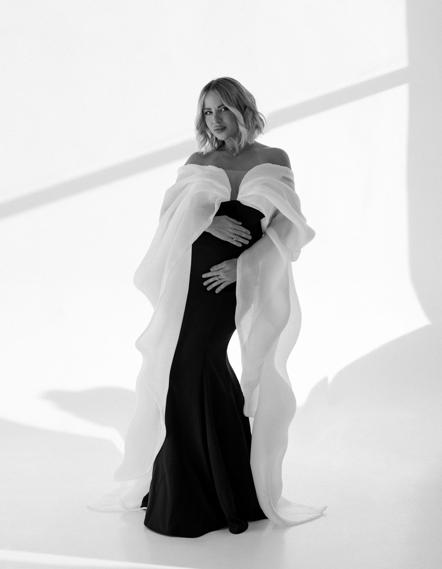 Chic and timeless maternity photography capturing a mother’s glow in a flowing black and white dress.