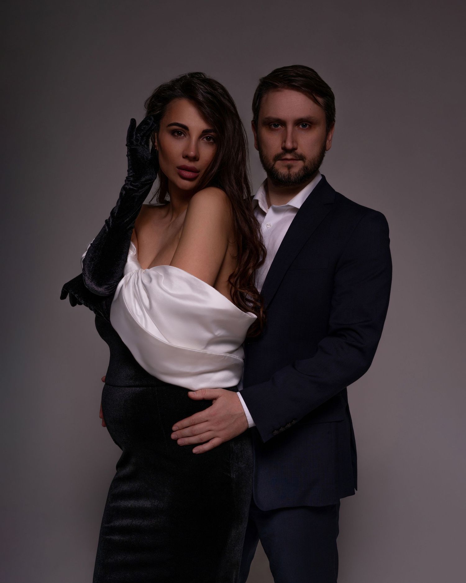 Artistic maternity photo showcasing the deep bond between expecting parents, the mom to be is wearing an elegant black and white dress.