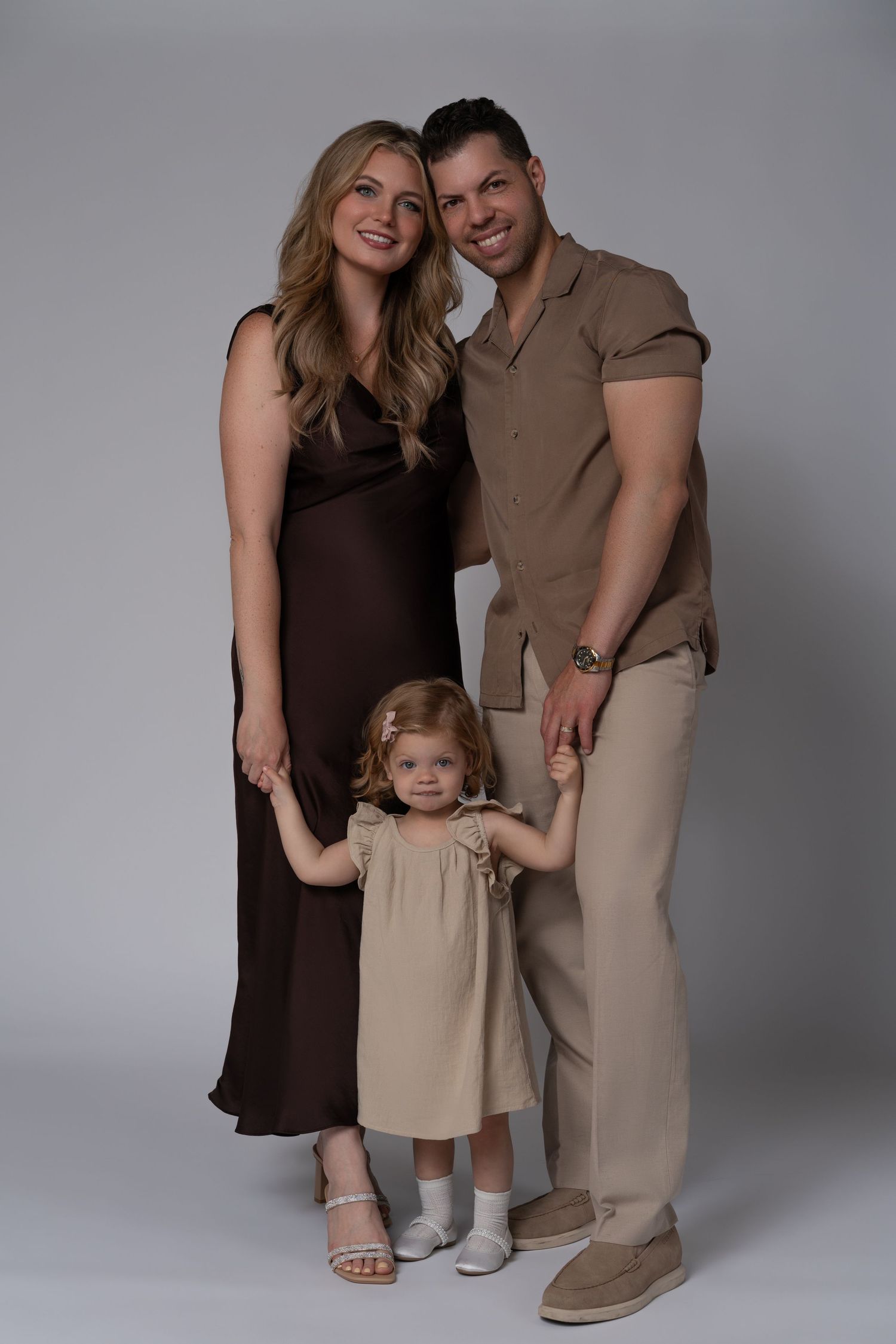 Family portrait in Chicago — young parents with their 3-year-old daughter dressed in beige and brown outfits.