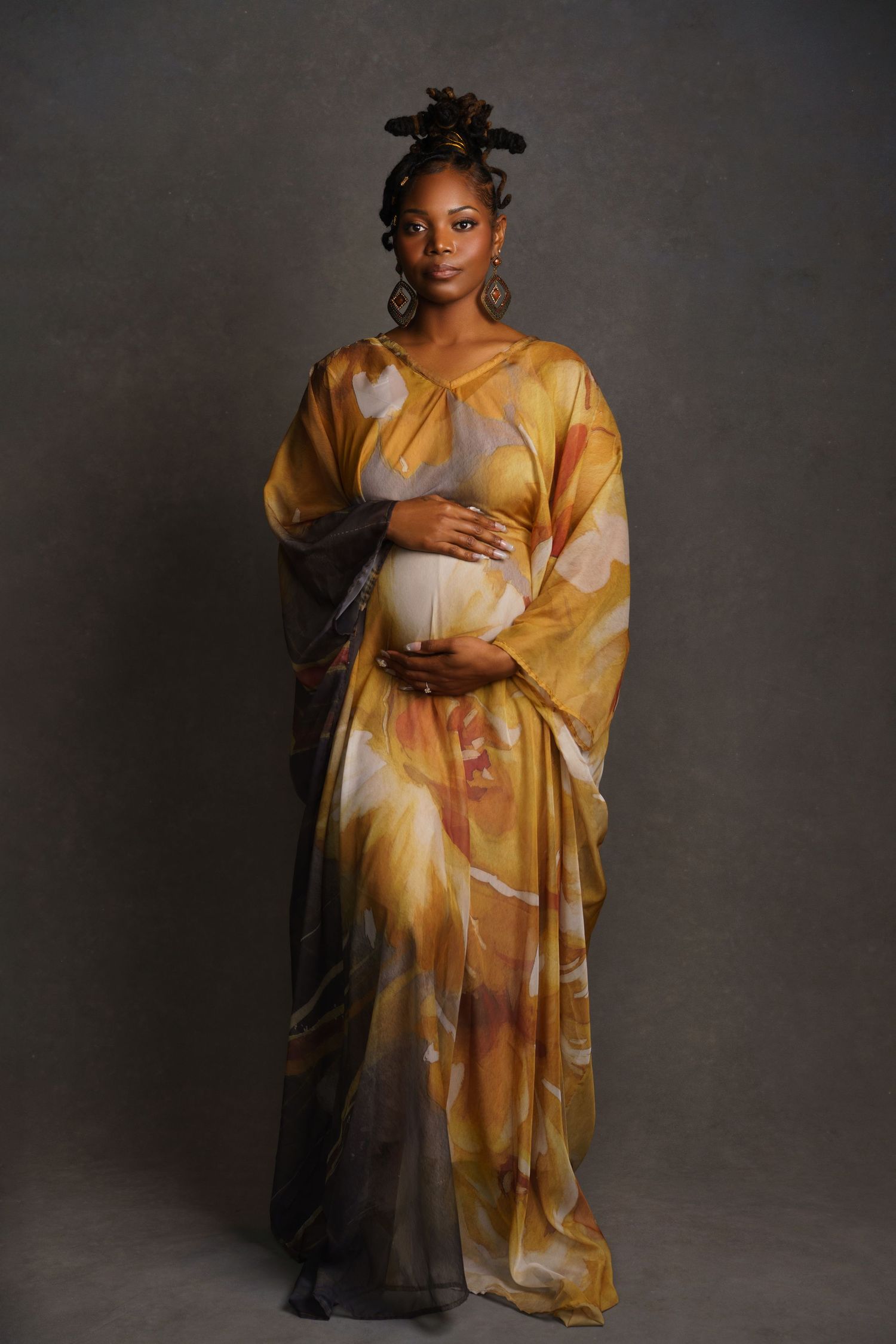 African American mom-to-be in a long ethnic dress with traditional hairstyle — powerful and cultural maternity portrait in a Chicago studio.