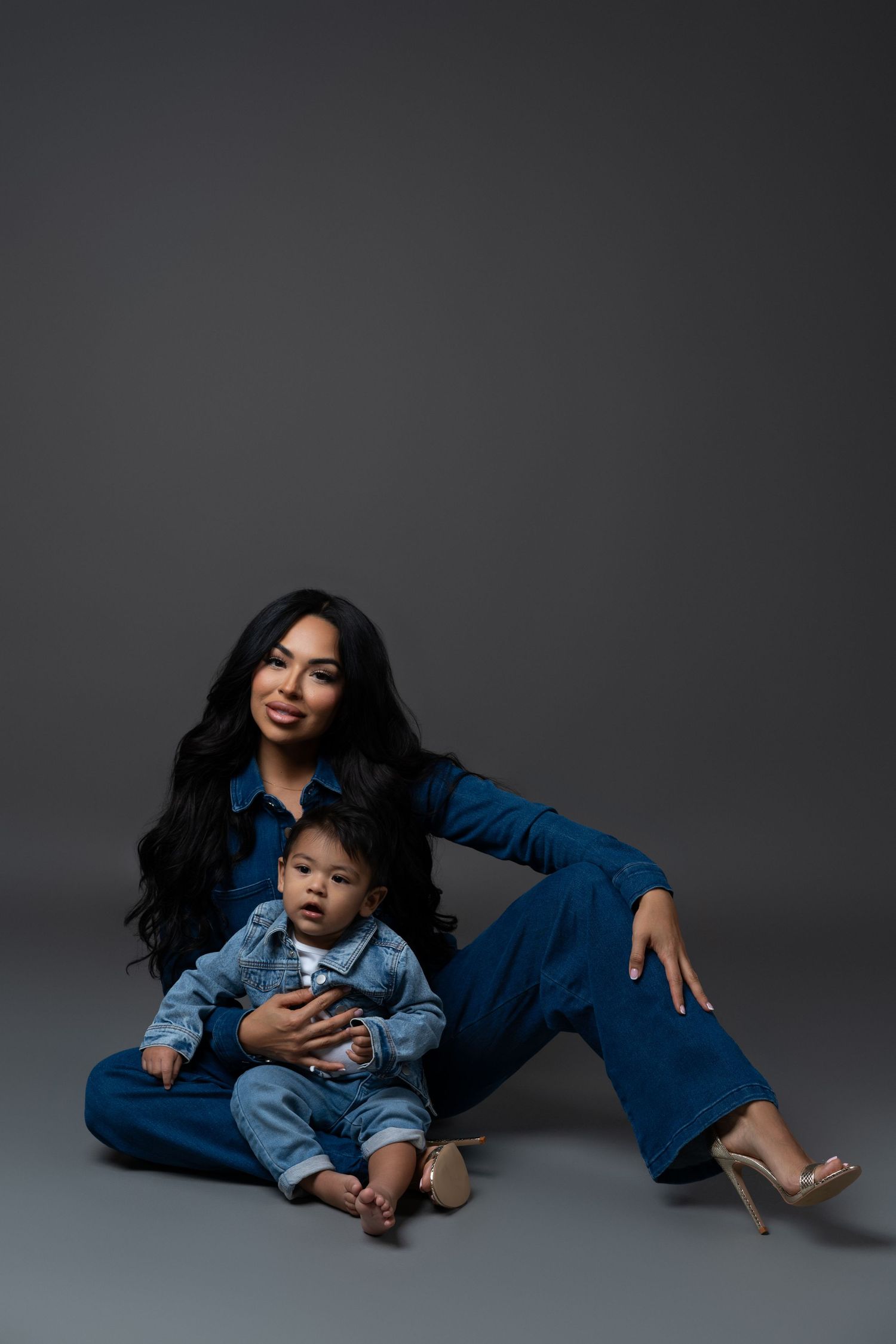 Mommy and me session posing on the studio floor in Chicago in total denim looks. Son is one year old.