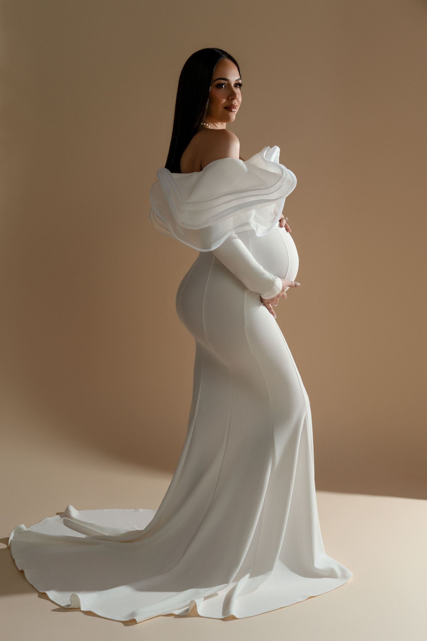 Iconic maternity portrait of a sophisticated expectant mother in a white statement dress during her luxury photoshoot in Chicago.