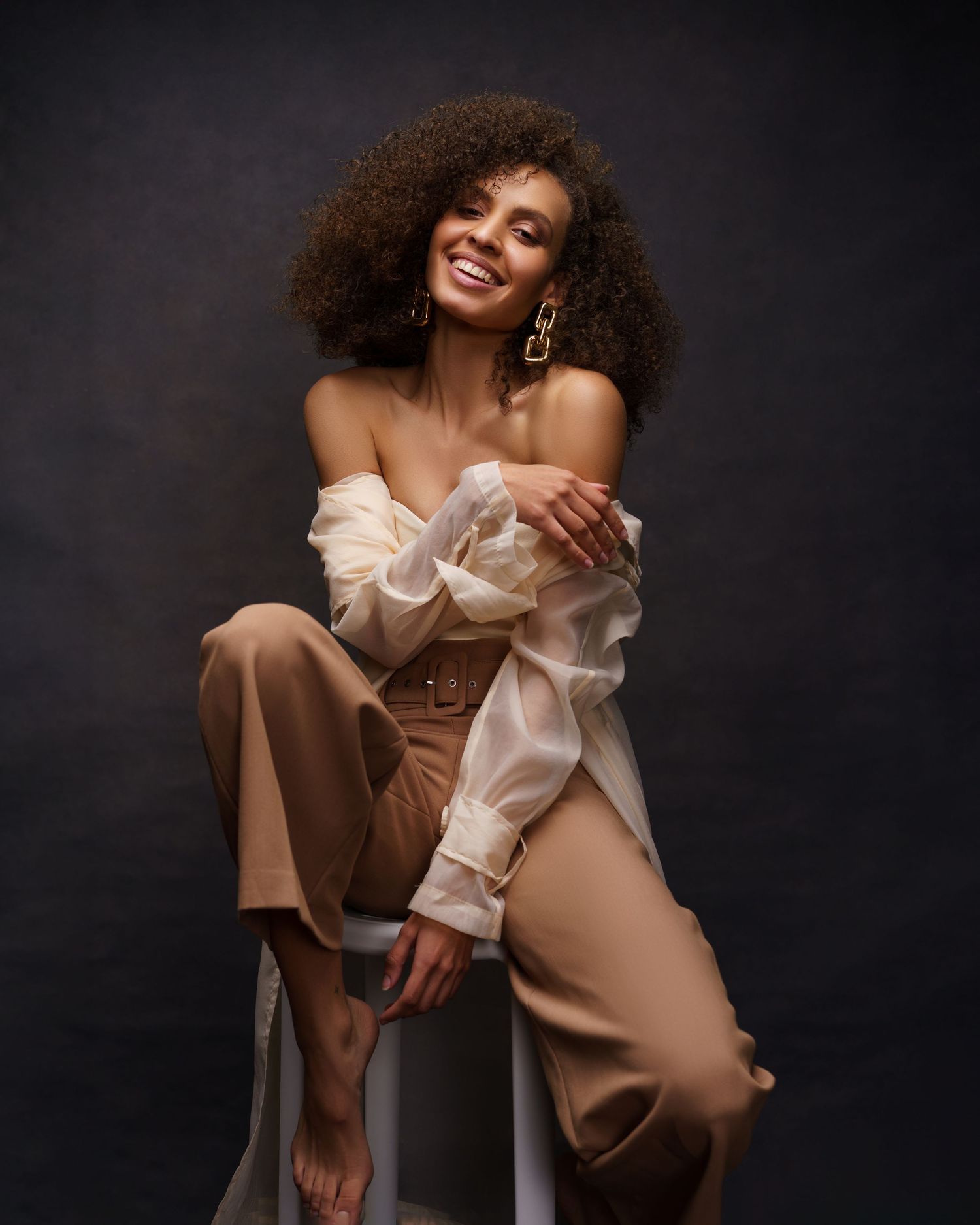 Young African American woman with curly hair posing for a glamorous fashion photoshoot in Chicago — confident, relaxed, and radiant.