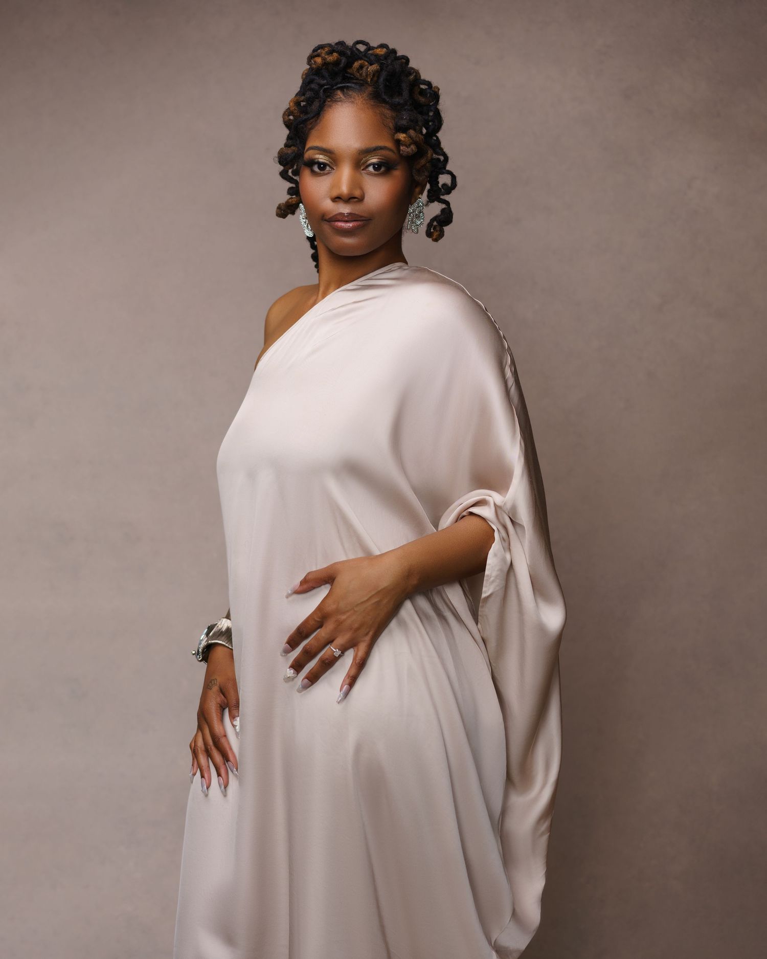 Black woman posing in a Chicago photo studio wearing a beige silk dress — elegant studio portrait.