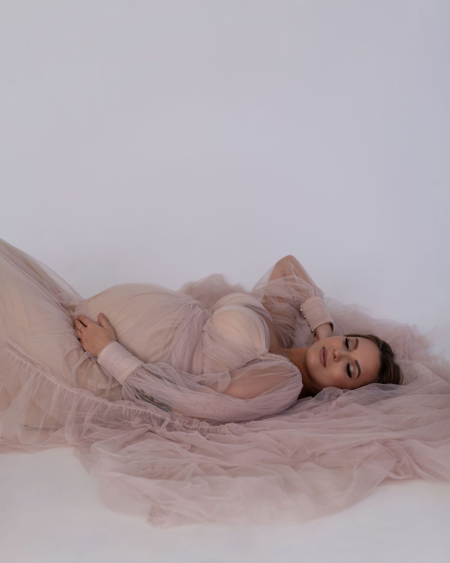 Pregnant women is posing in beige mesh gown during maternity photoshoot in Chicago.