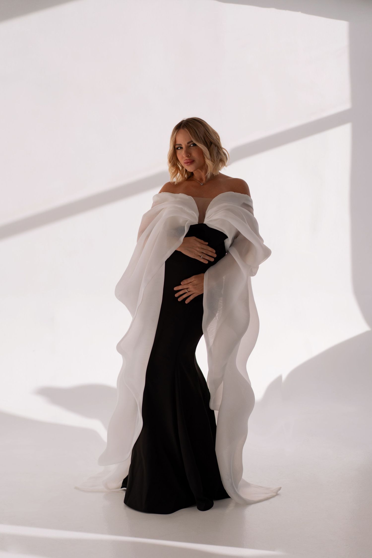 Chic and timeless maternity photography capturing a mother’s glow in a flowing black and white dress.