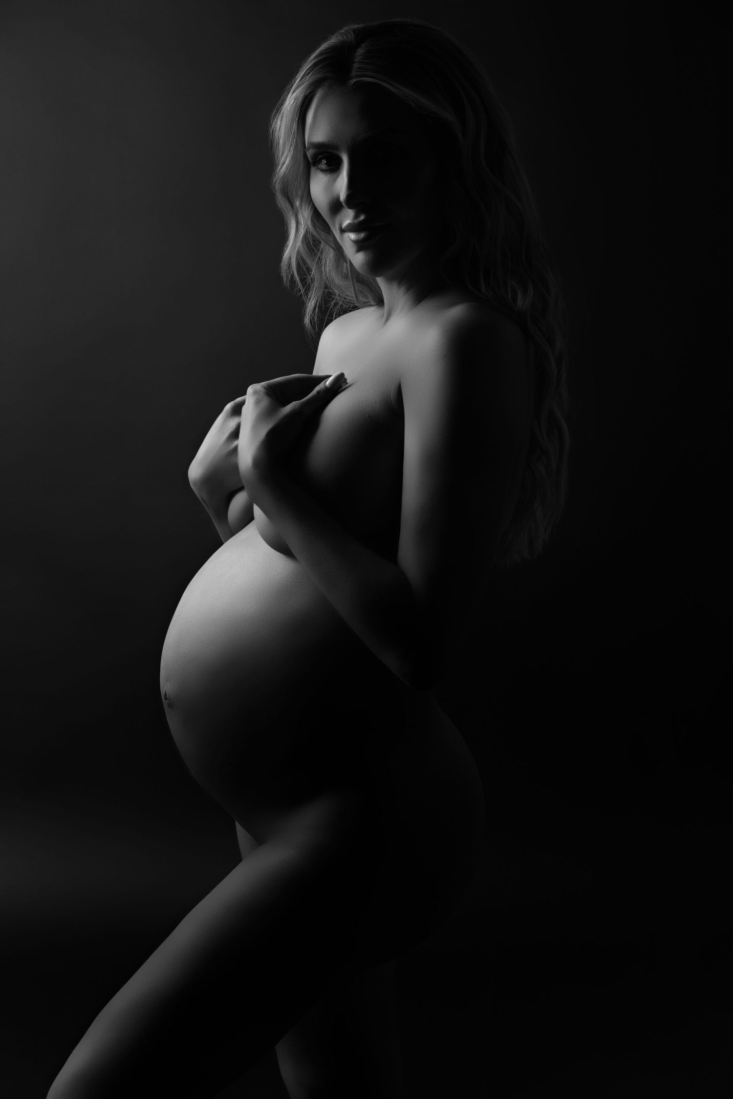 Striking black-and-white nude portrait of a blonde pregnant woman — graceful and refined pose captured in a fine art maternity session.