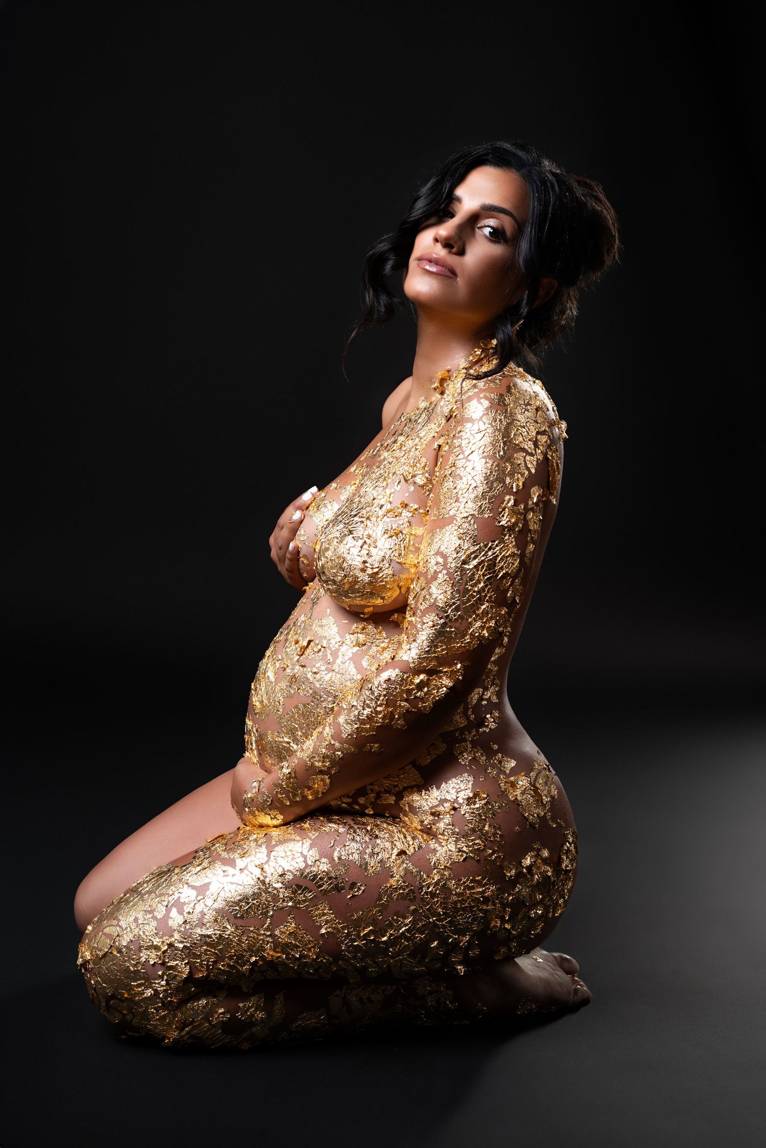 Maternity photoshoot in nude style with gold foil accents in a Chicago studio.