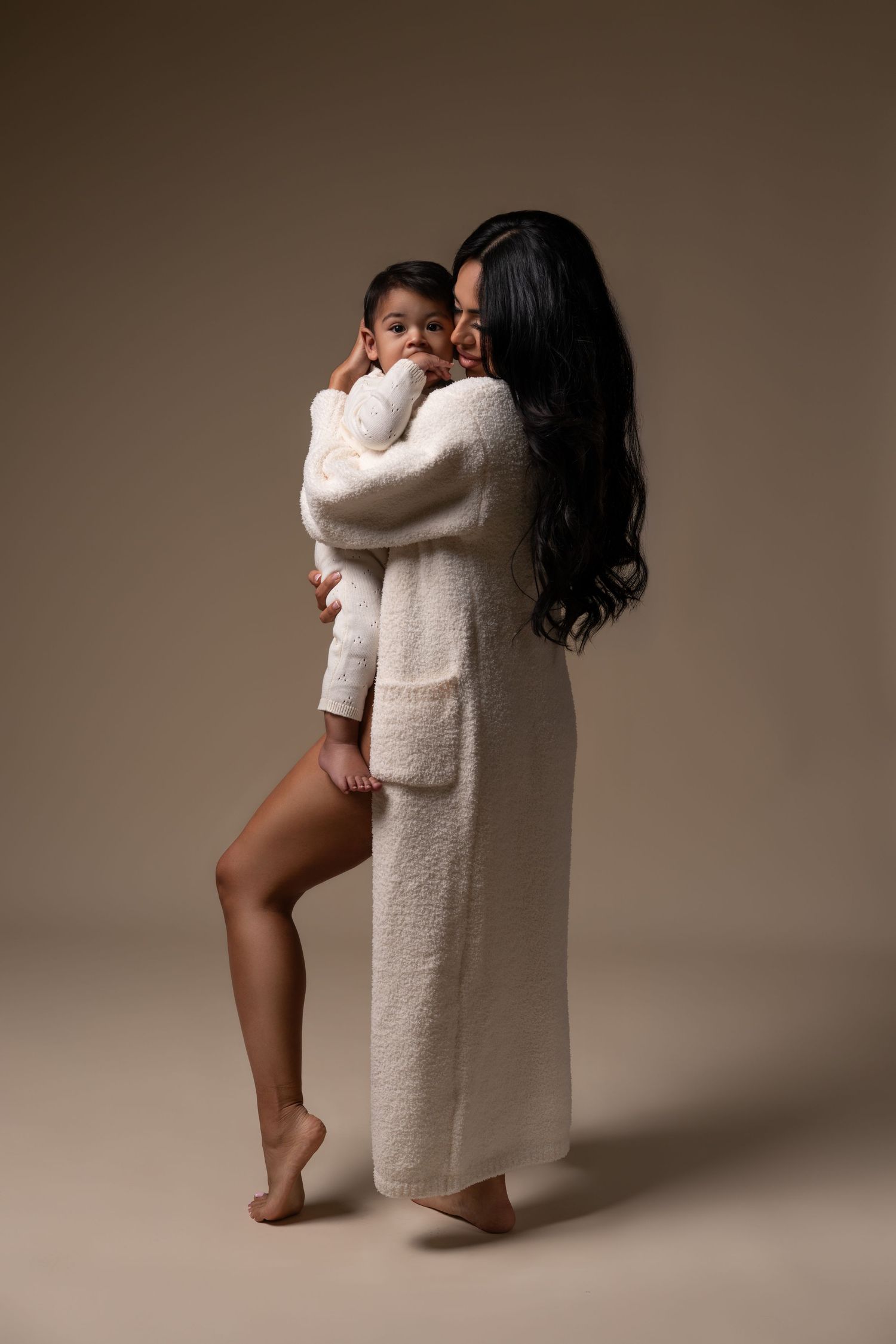 Cozy mommy and me session with mom and son posing in a Chicago studio. Mother and son in white sweaters.