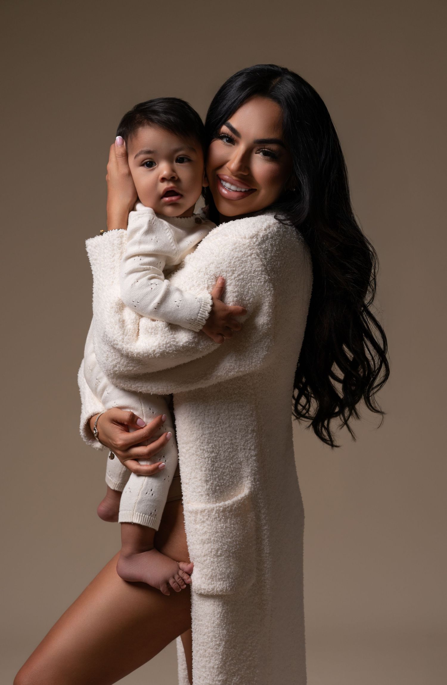Mommy and me session with one-year-old son wearing white outfits in a Chicago studio during photoshoot.