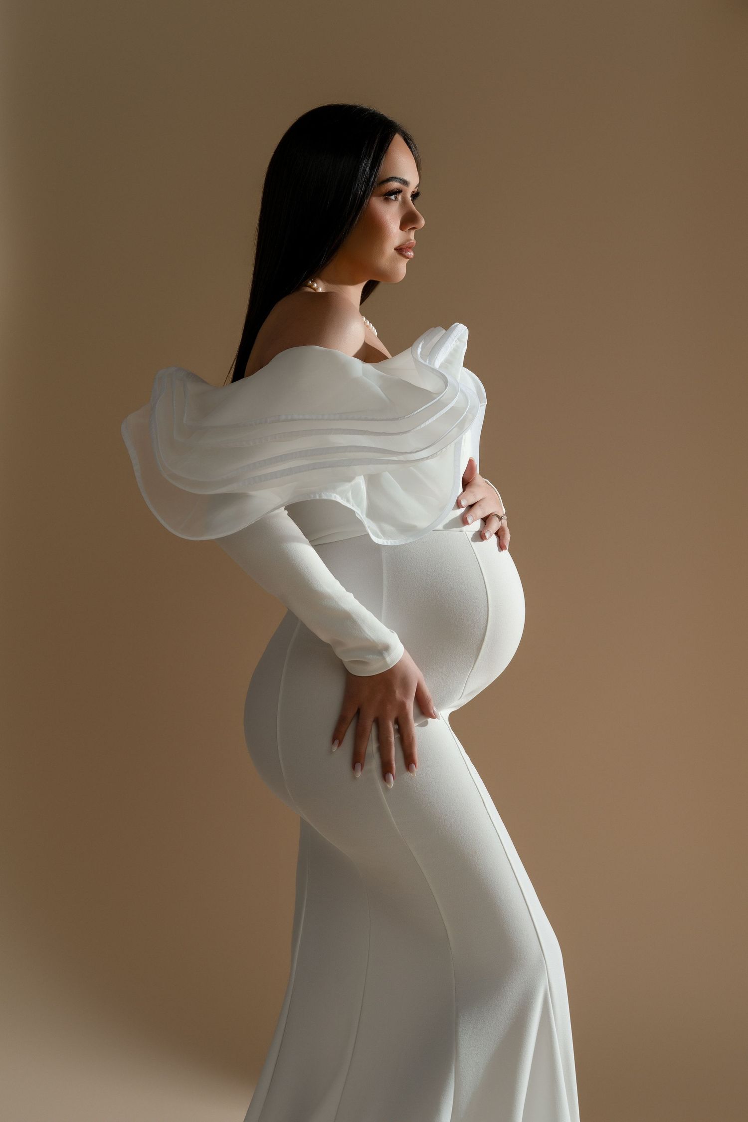 Beautiful pregnant woman wearing a white statement dress with ruffles during her maternity photoshoot in Chicago.