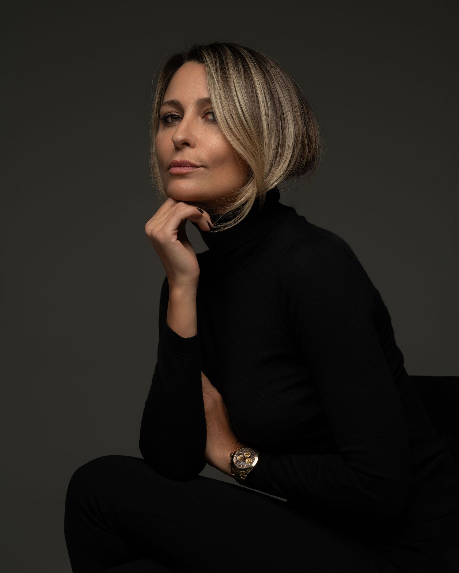 Classic female portrait made in Chicago photo studio of a blonde woman in a black sweater on a dark background — minimalist and expressive.