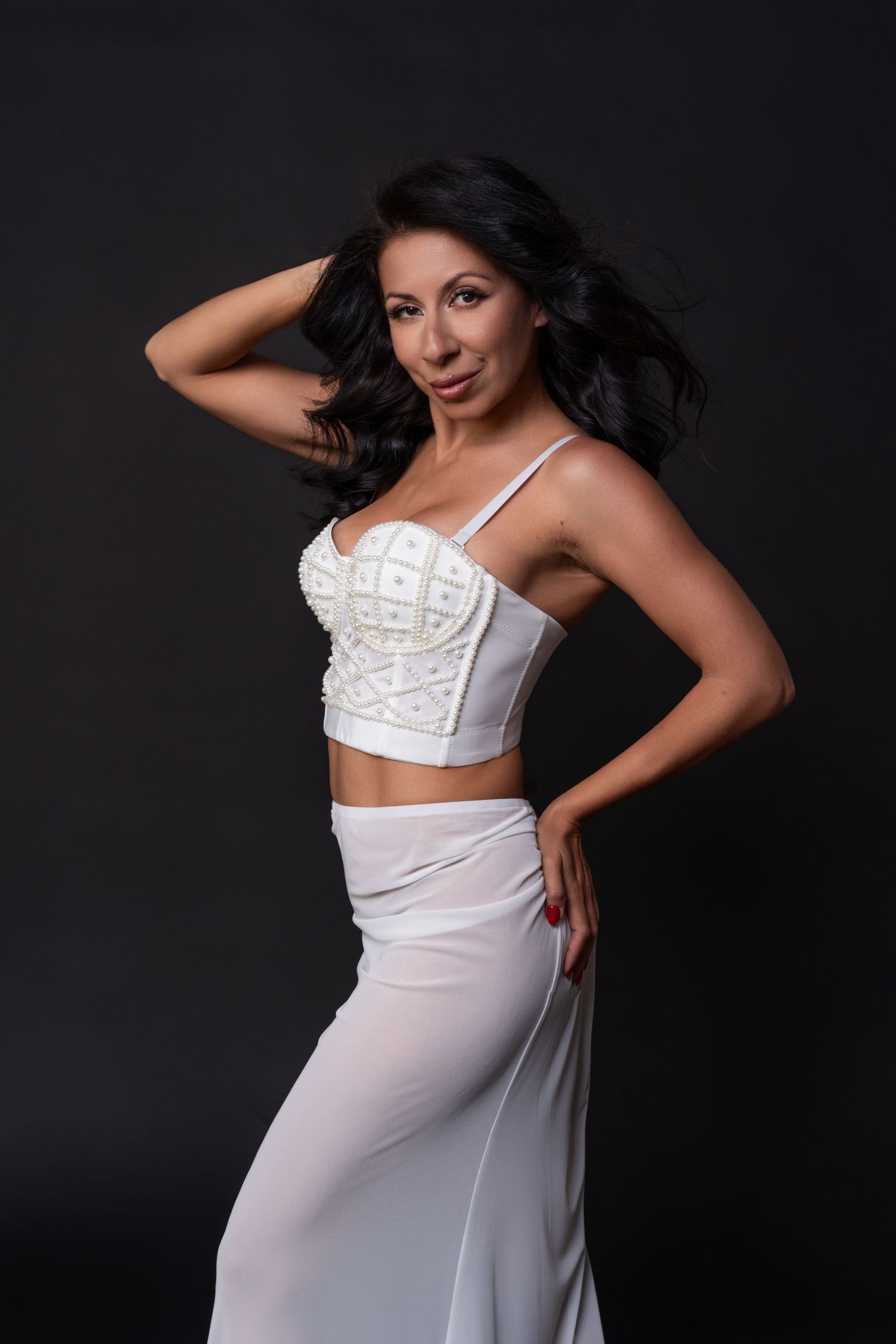 Beautiful brunette in a white luxury suit posing against a black background in a high-end Chicago photo studio.