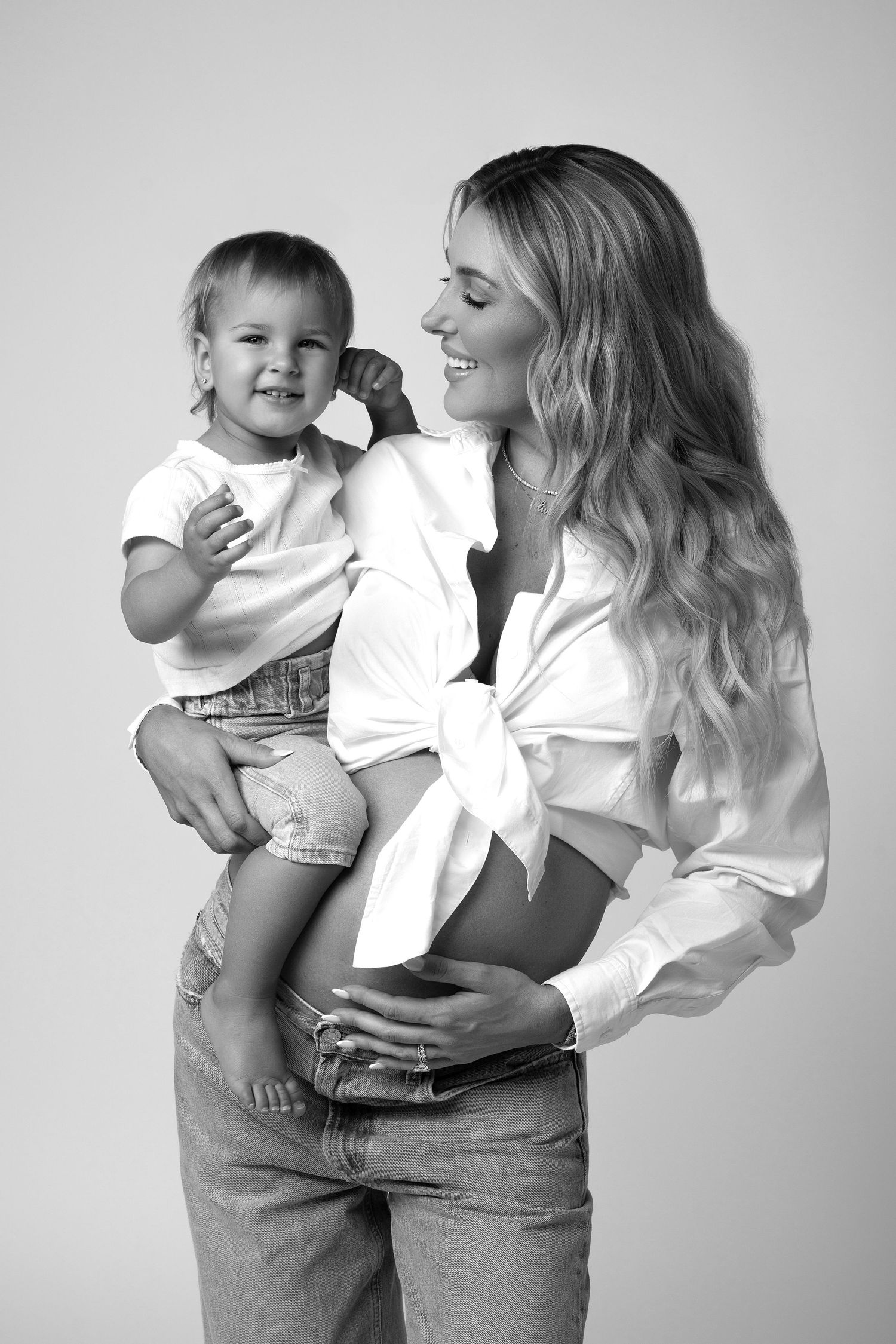 Black and white portrait of mother and daughter posing in jeans and white shirts in a Chicago studio during a mommy and me session.