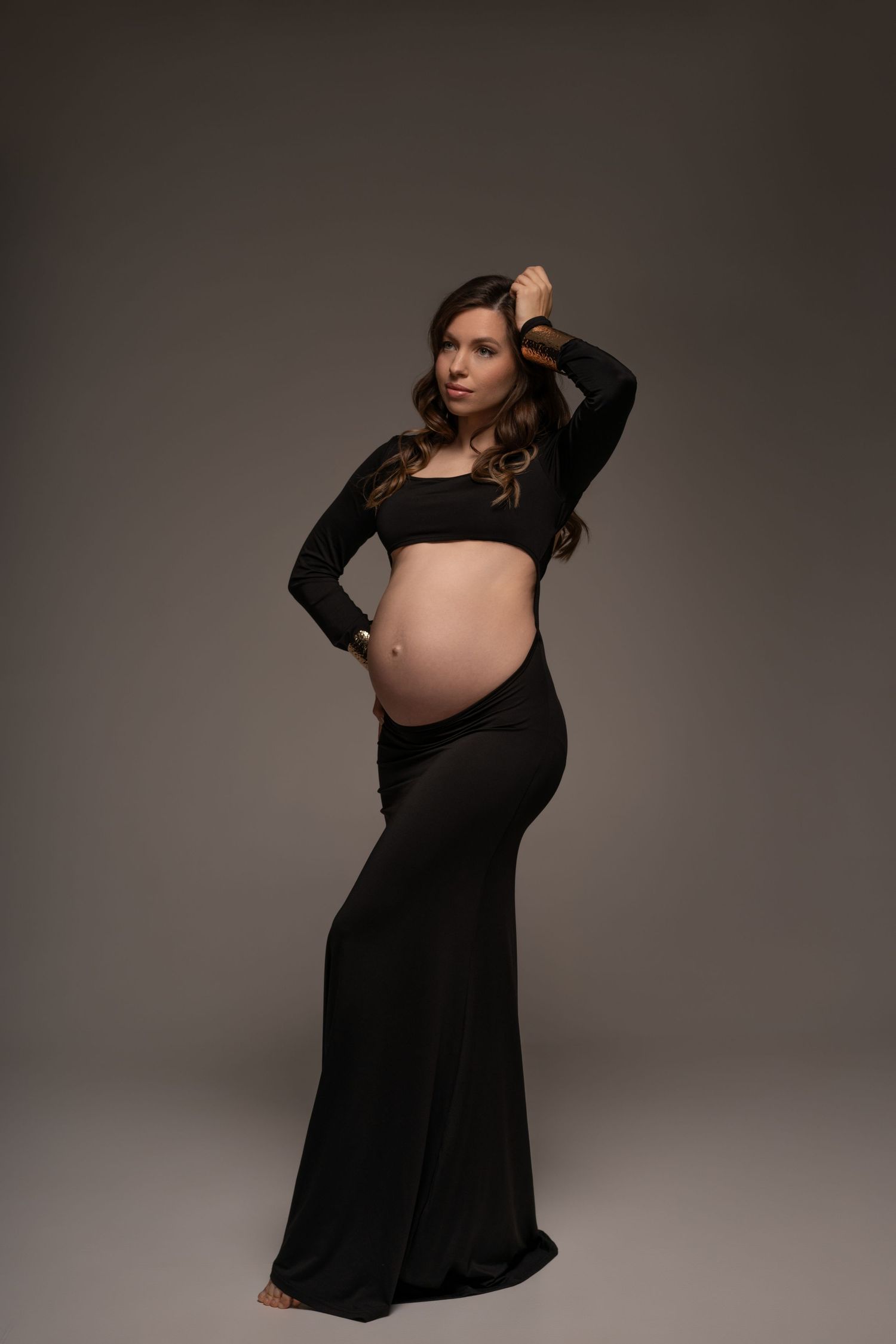 Maternity portrait of a stylish expecting mother posing in long black dress with confidence and grace in Chicago studio.
