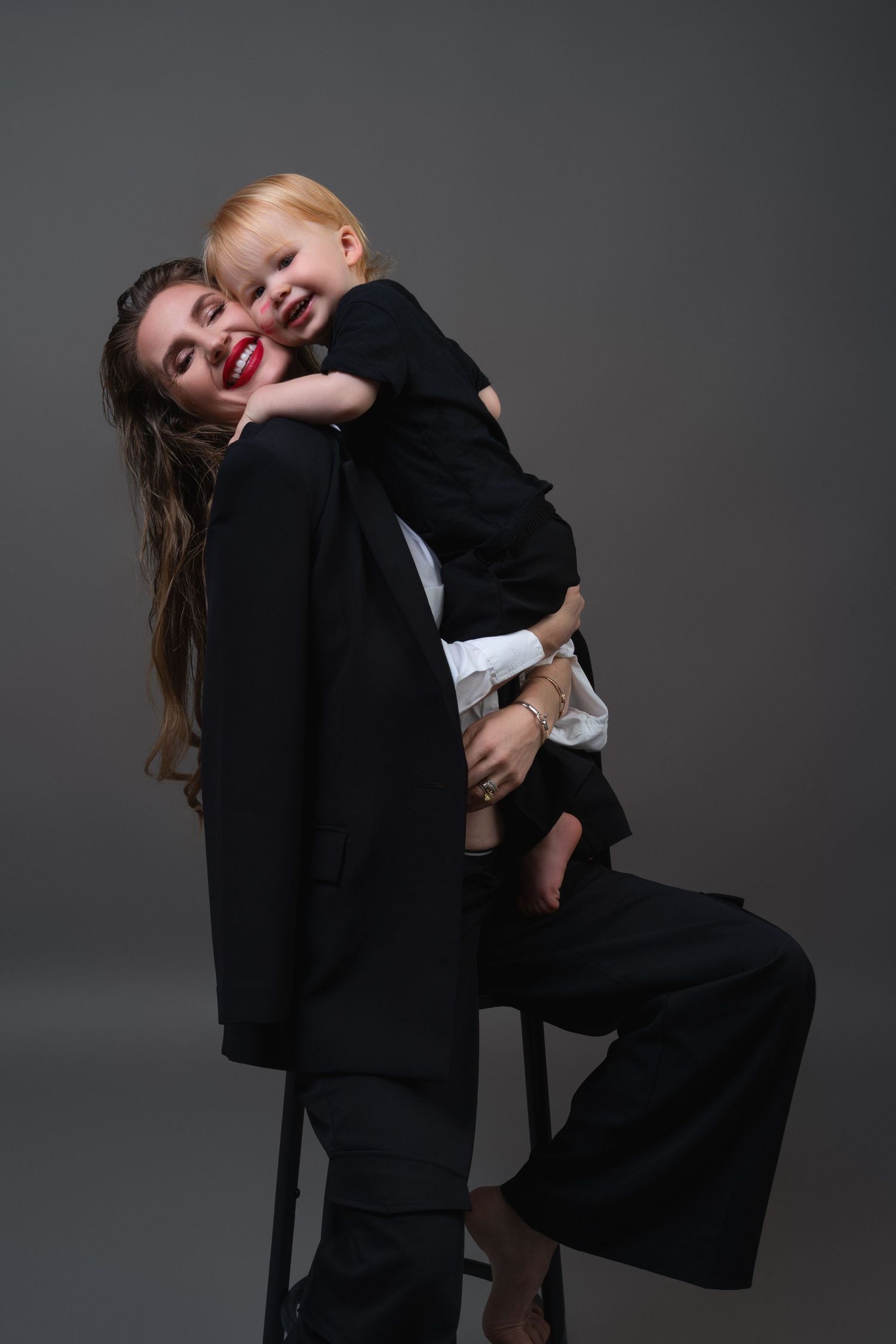 Stylish Mommy and Me studio session in Chicago with a mother in a tailored black suit and bold red lipstick sharing a moment with her son.