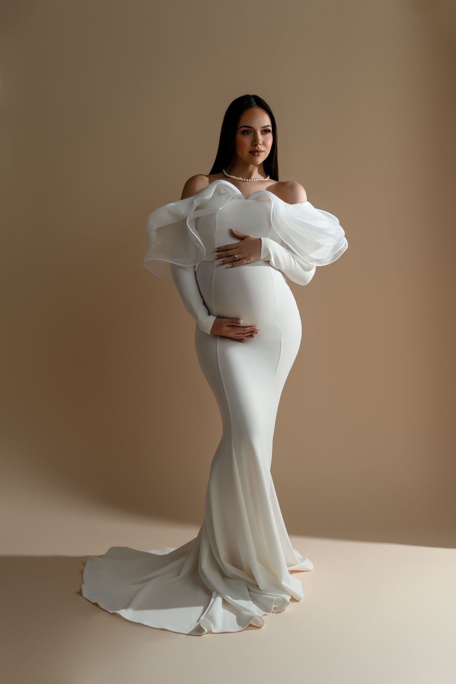 Elegant mom-to-be posing in a white ruffled gown during her luxury maternity photography session in Chicago.