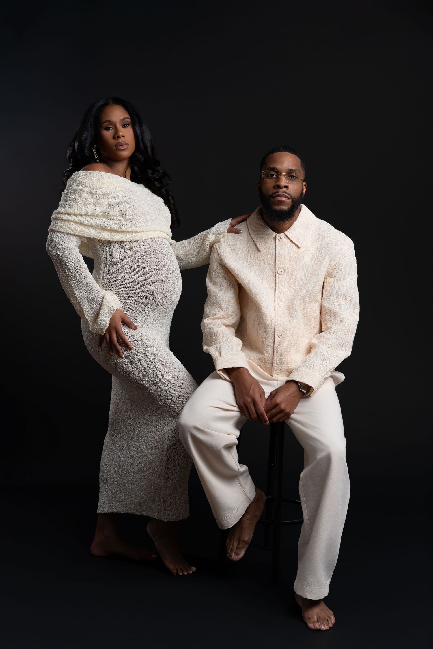 African American expectant couple dressed in white, posing together during their maternity photography session in Chicago.